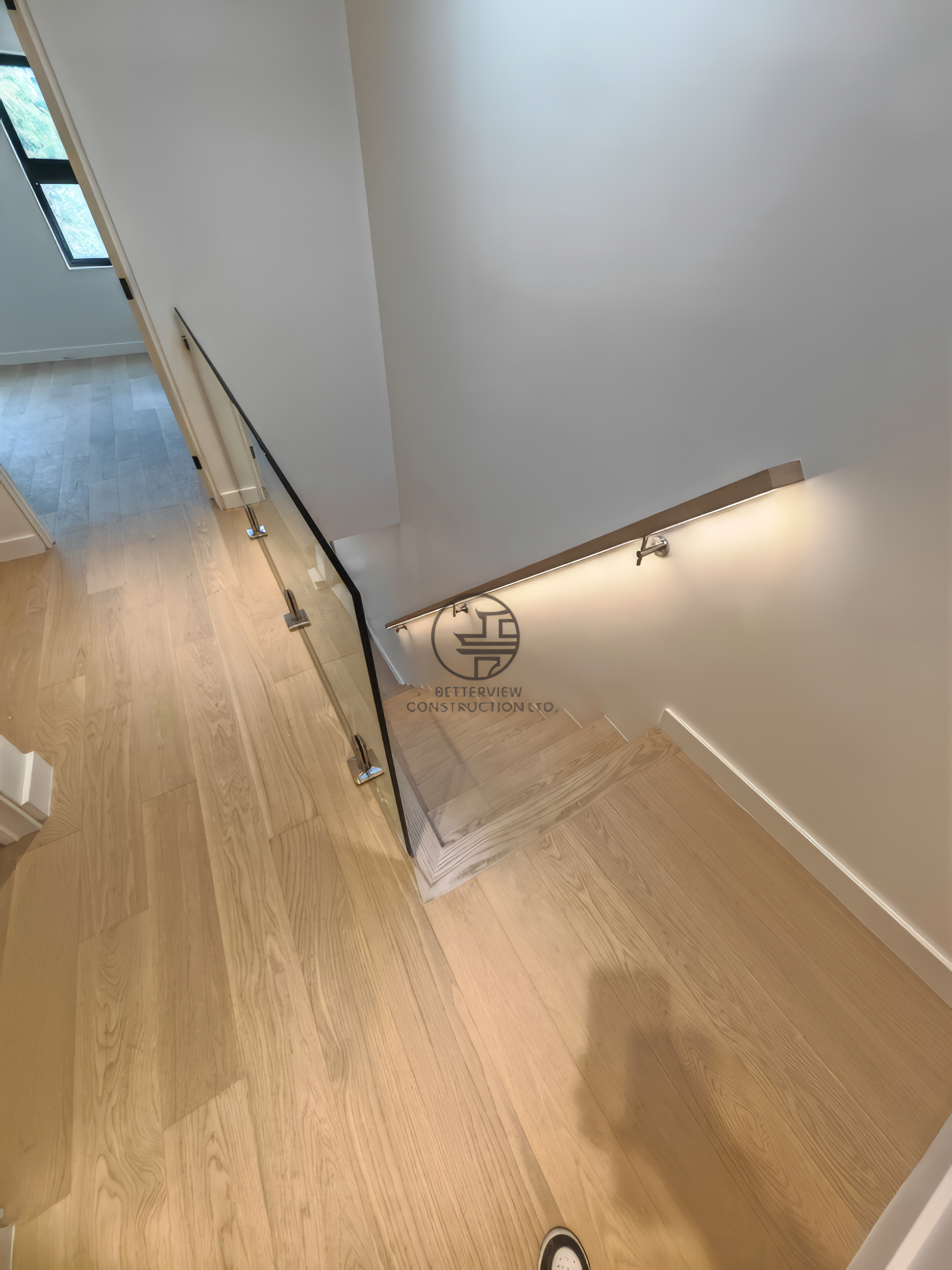 modern staircase with glass railing, wood steps, and built-in wall lighting in minimalist interior