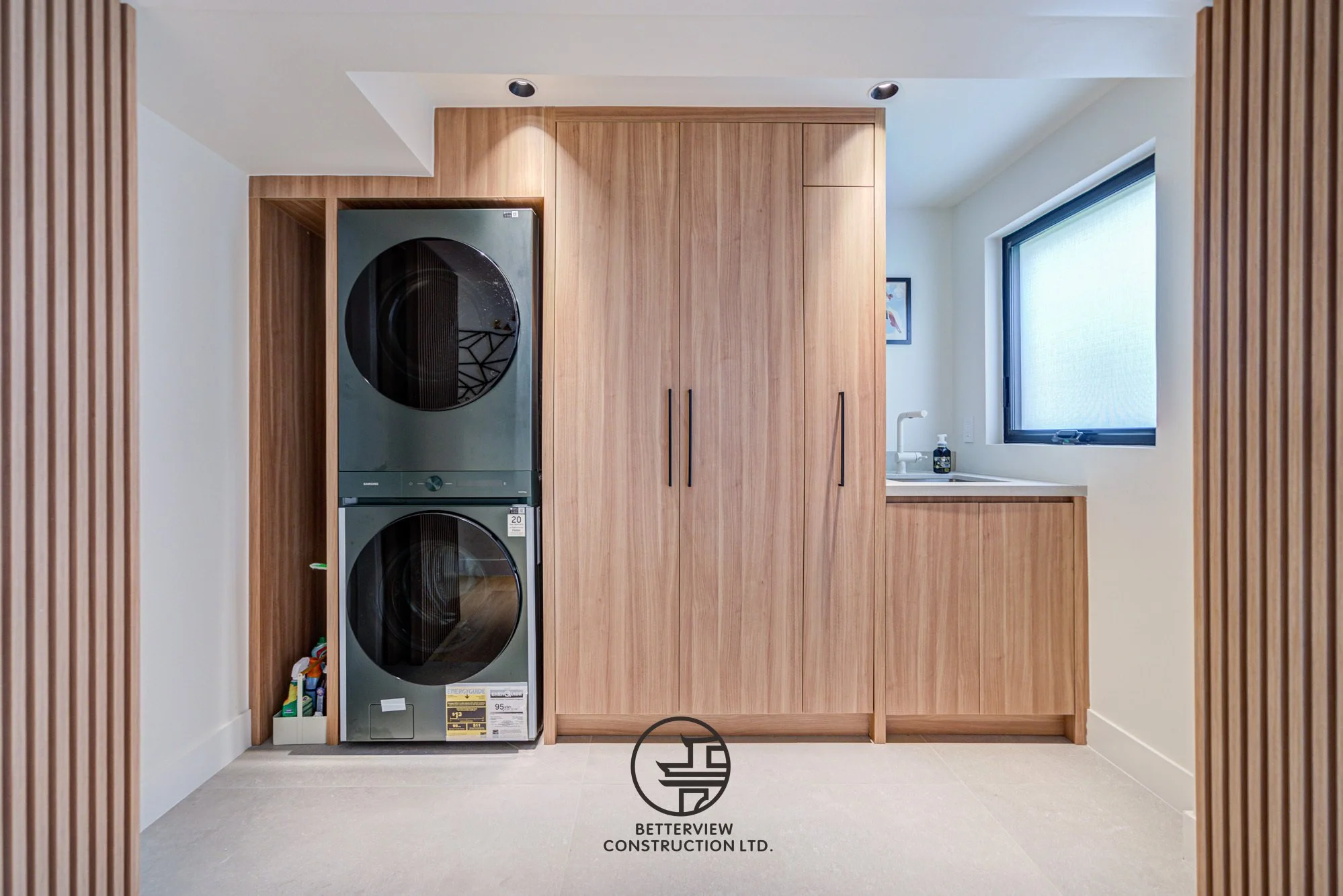 modern laundry room renovation with stacked washer dryer and custom wood cabinetry