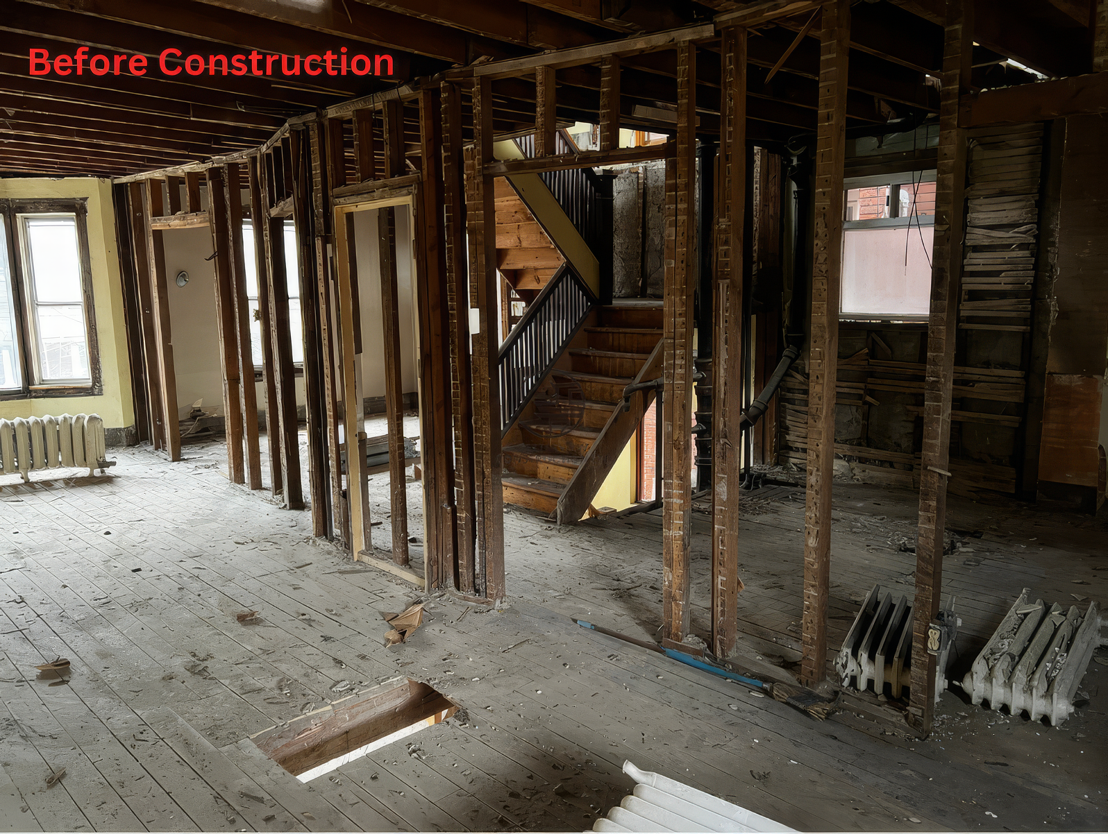 Before construction interior with exposed wood framing, open floor layout, staircase structure, and stripped flooring in a residential home renovation project
