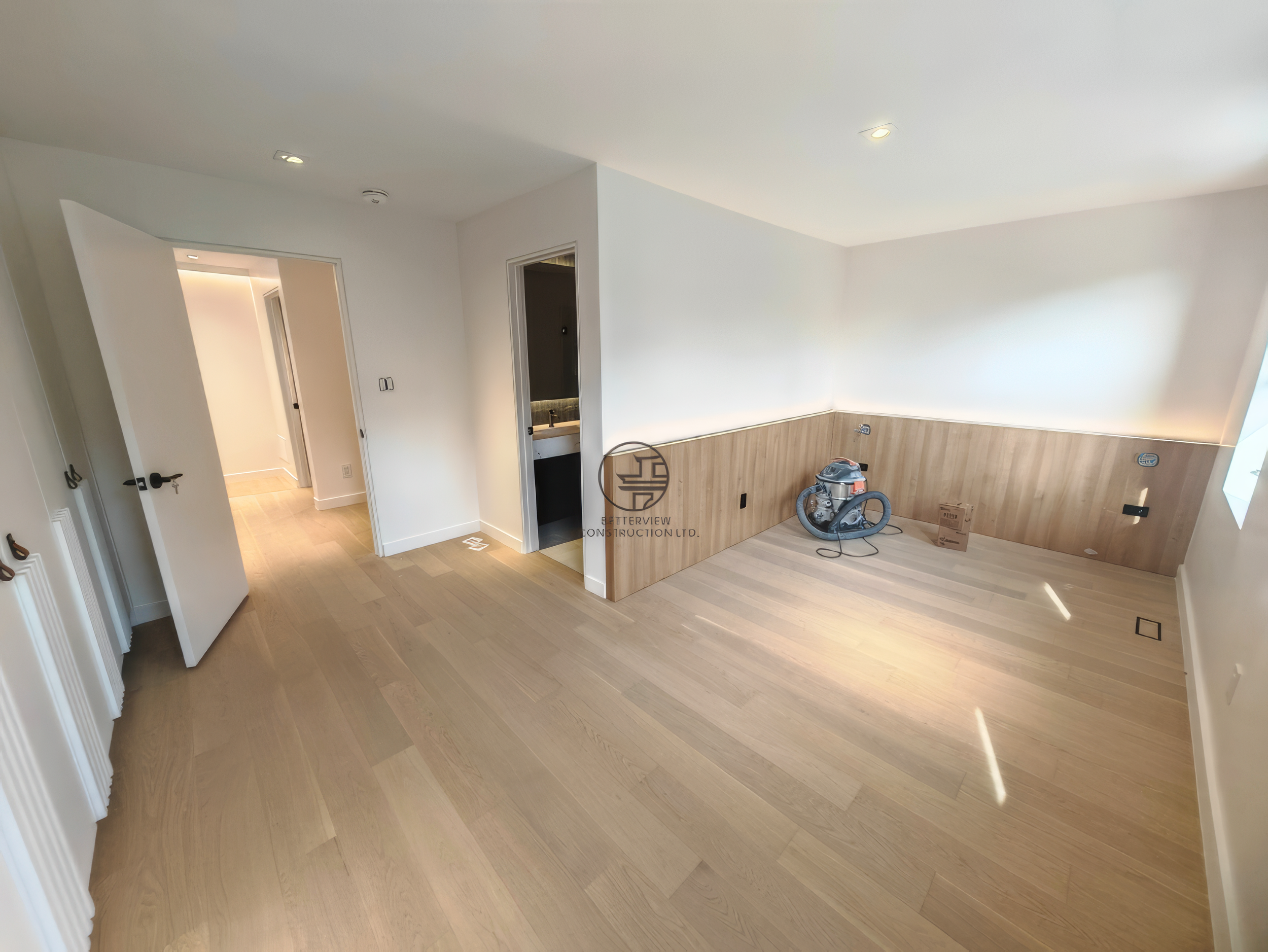 modern basement renovation room with light wood flooring, partial wood panel walls, and minimalist interior design