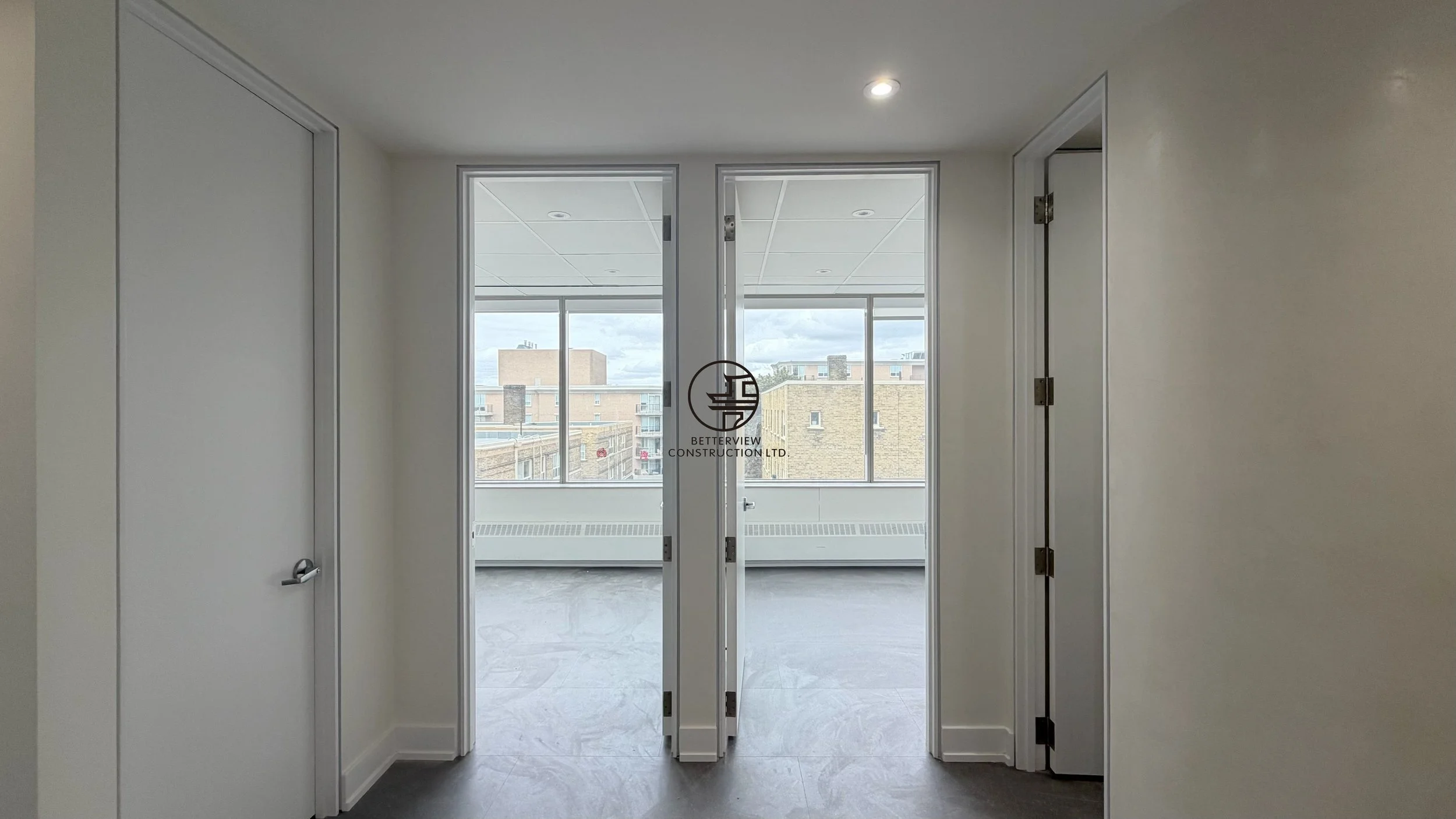 Office corridor with glass doors, natural light, and modern interior design in commercial renovation