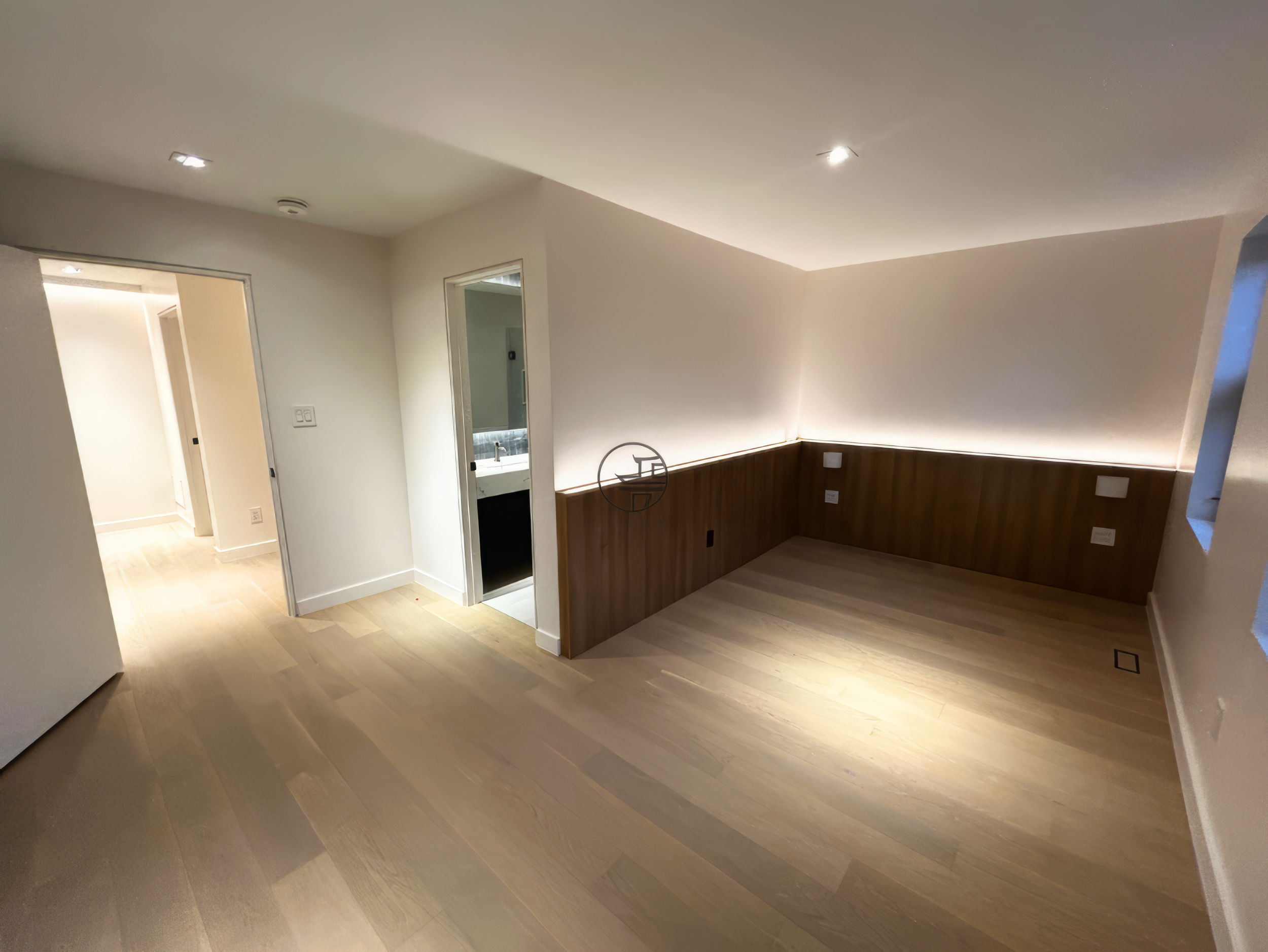 modern basement renovation room with wood panel accent wall, ambient lighting, and light hardwood flooring