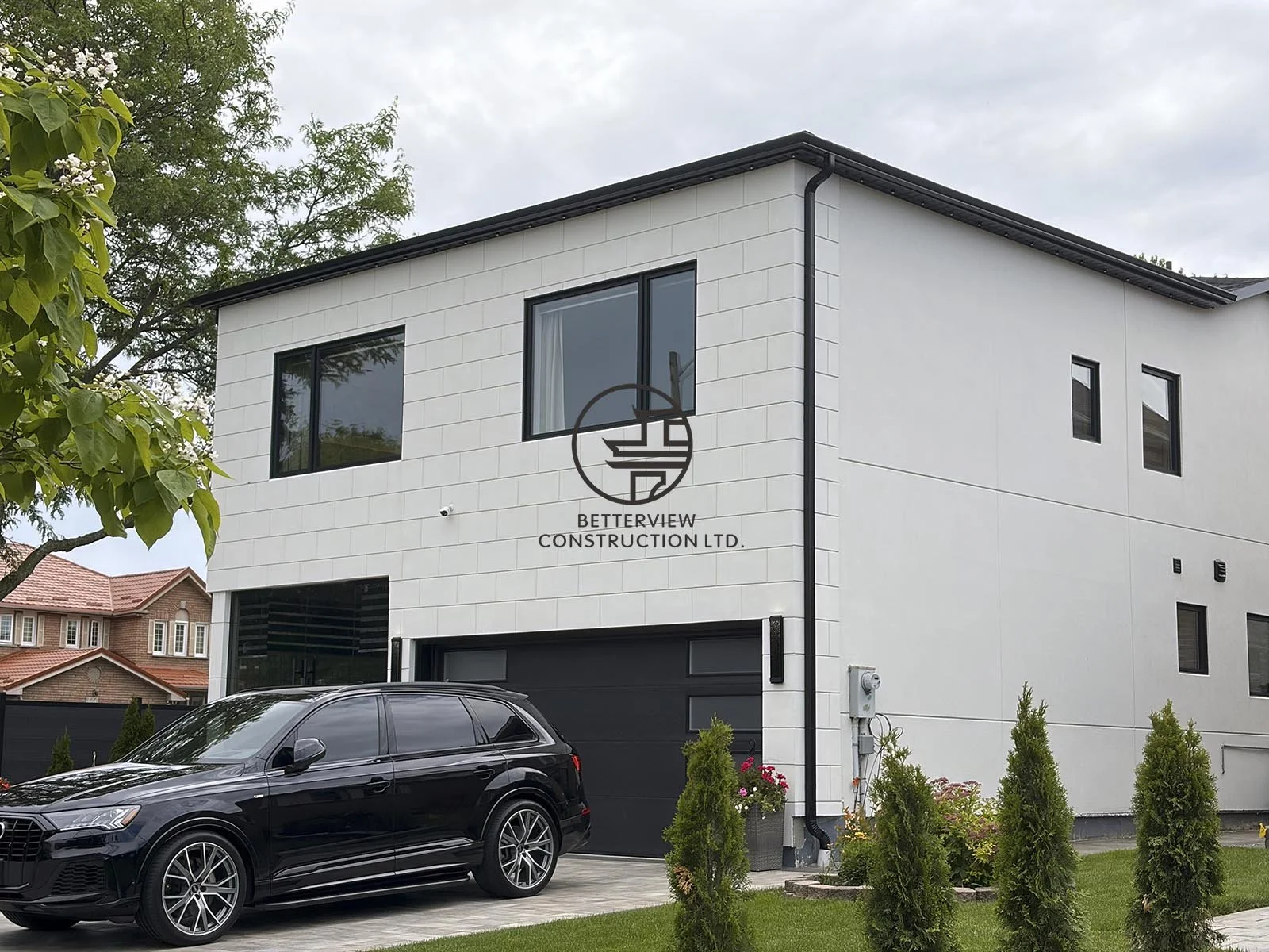 This side view highlights the contemporary addition, featuring sleek white cladding, oversized windows, and a cohesive exterior design that complements the original home.