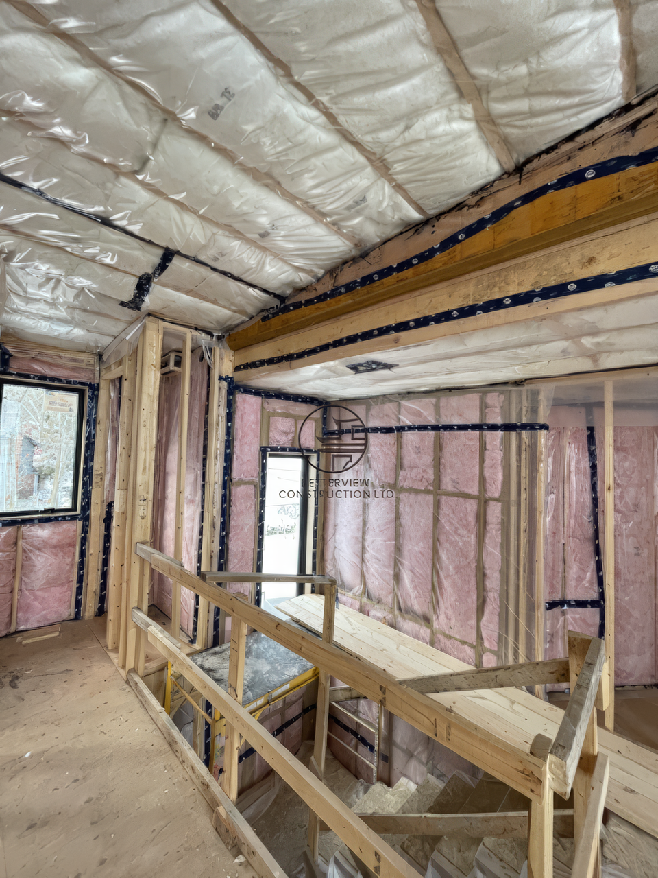 Interior framing and insulation during home renovation with exposed beams and staircase structure