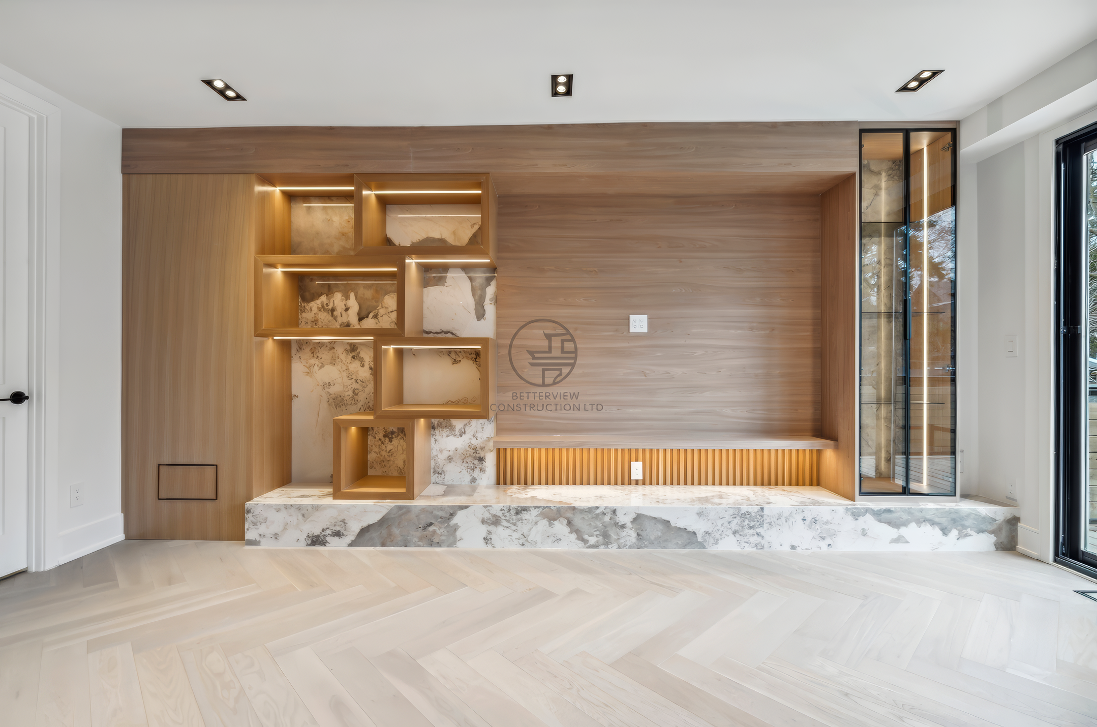 Modern feature wall with custom wood paneling, built-in shelving, marble base, and integrated lighting in a luxury home renovation project