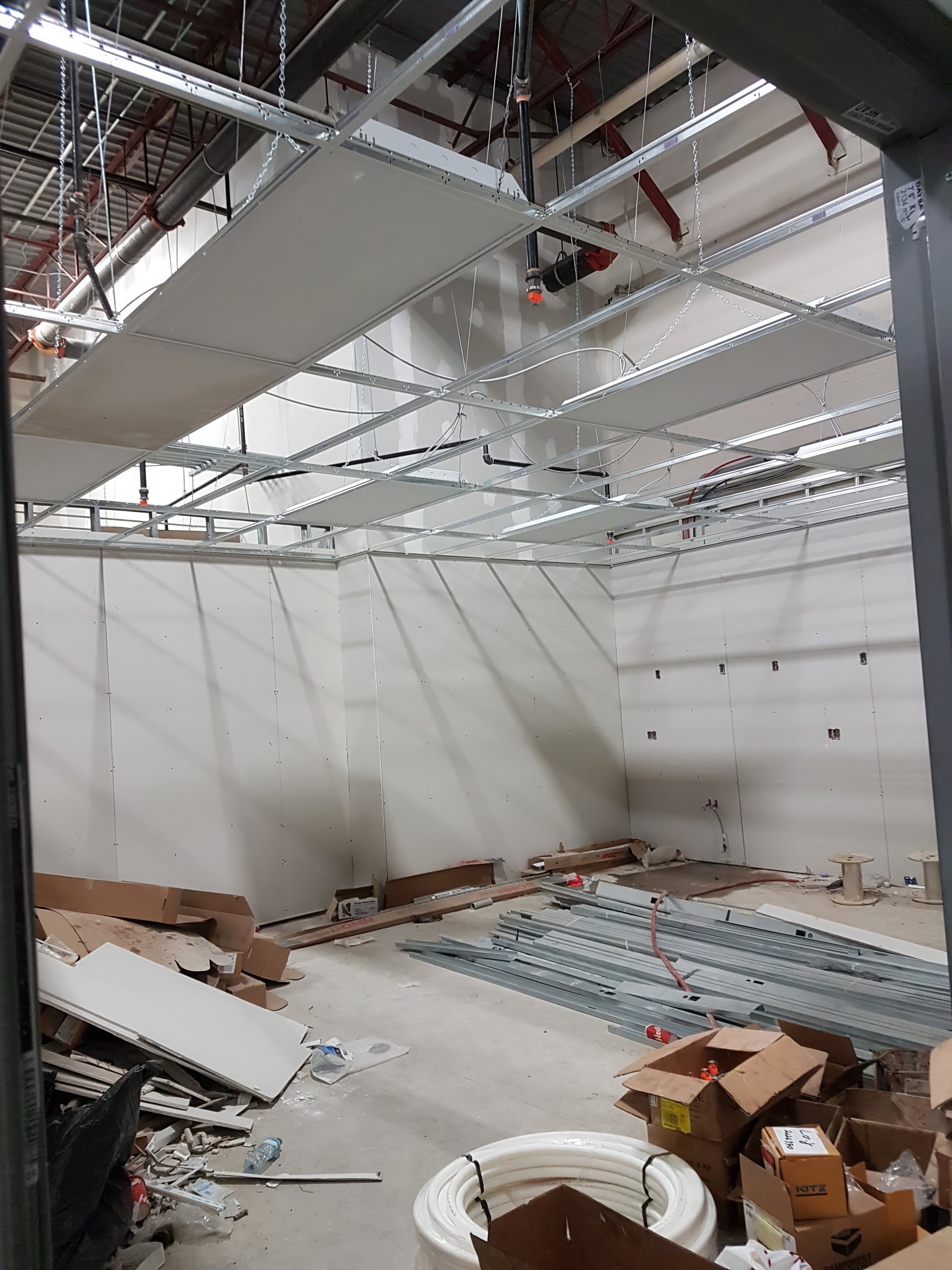 Commercial interior build-out showing completed drywall walls and suspended ceiling installation with integrated systems in a Toronto renovation project