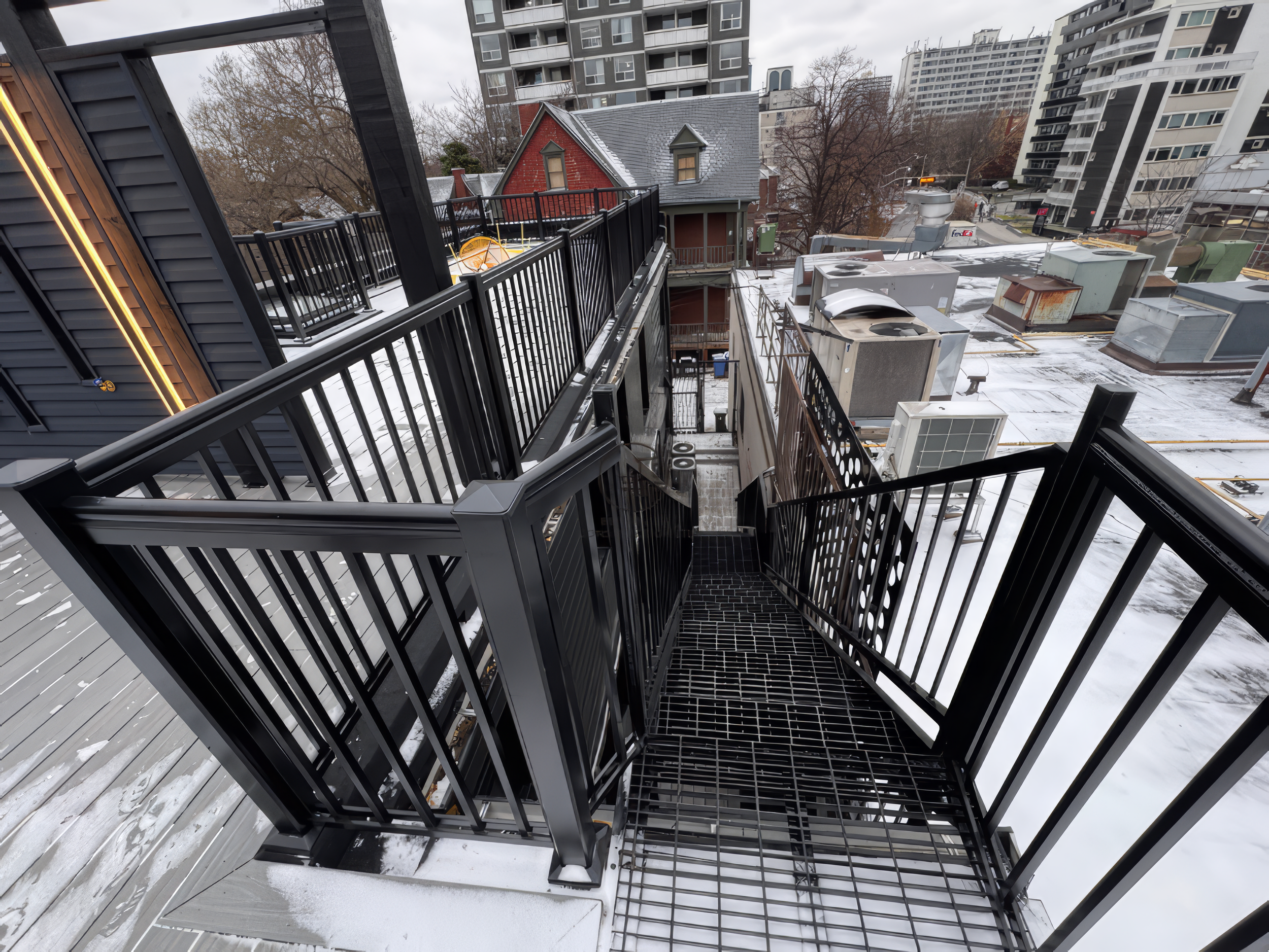 Exterior metal staircase with black railing in a Toronto renovation project, showing rooftop access and safety design