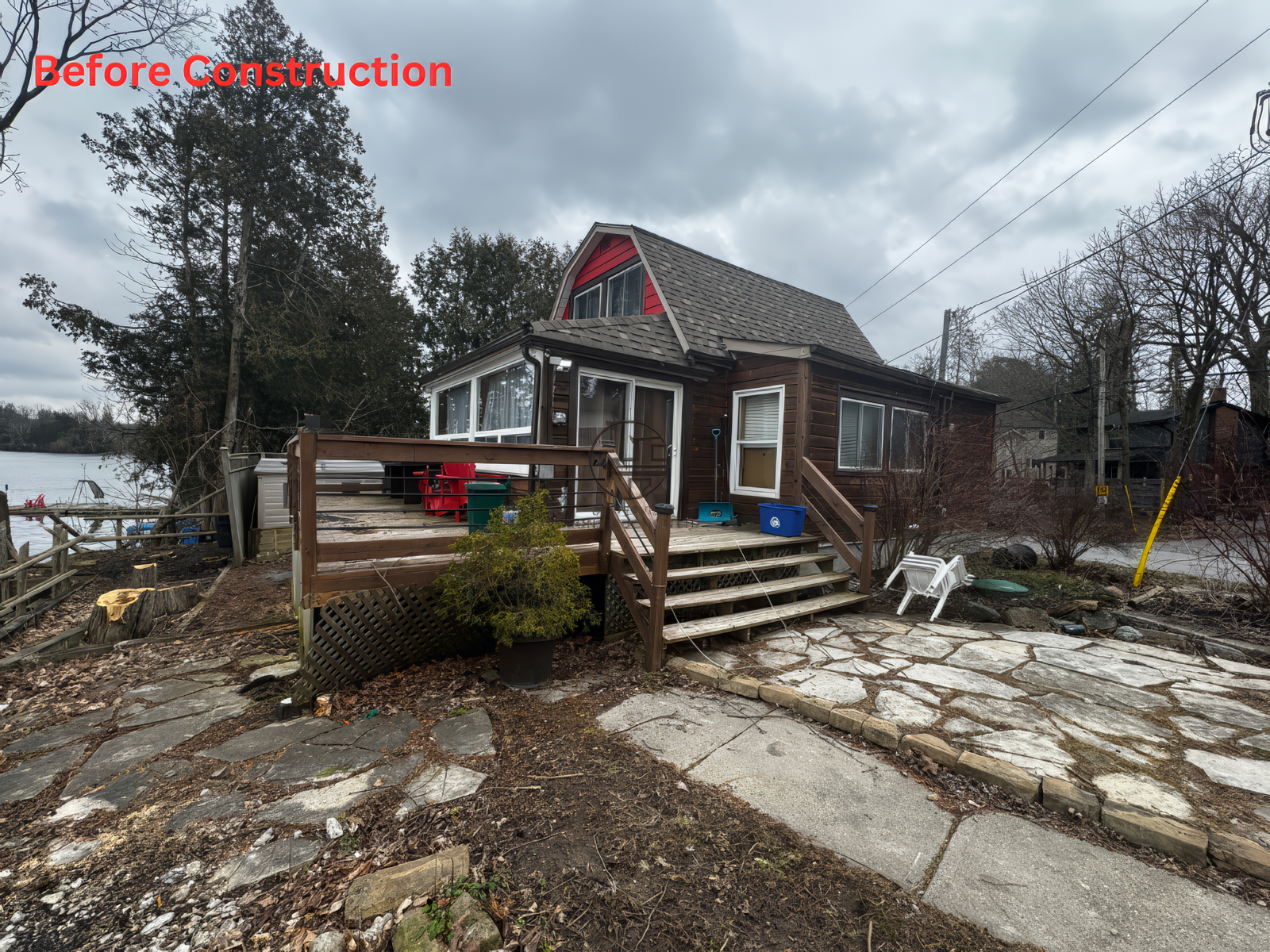 Before construction view of lakeside house with wooden deck, outdoor stairs, and yard