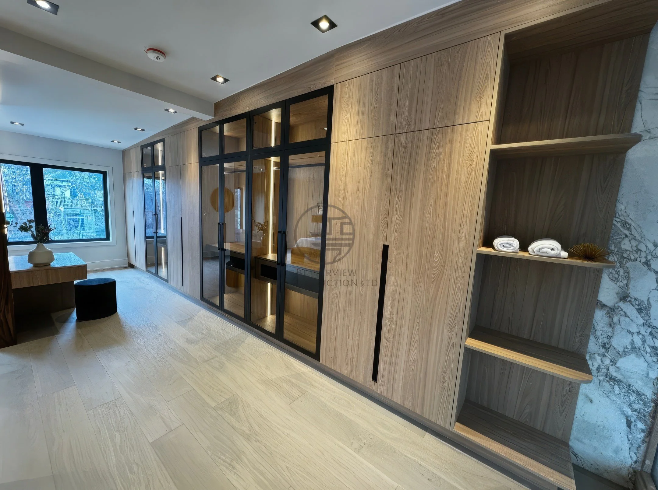 Modern interior with custom wood wardrobe, glass-panel closet doors, open shelving, and recessed lighting in a luxury home renovation project