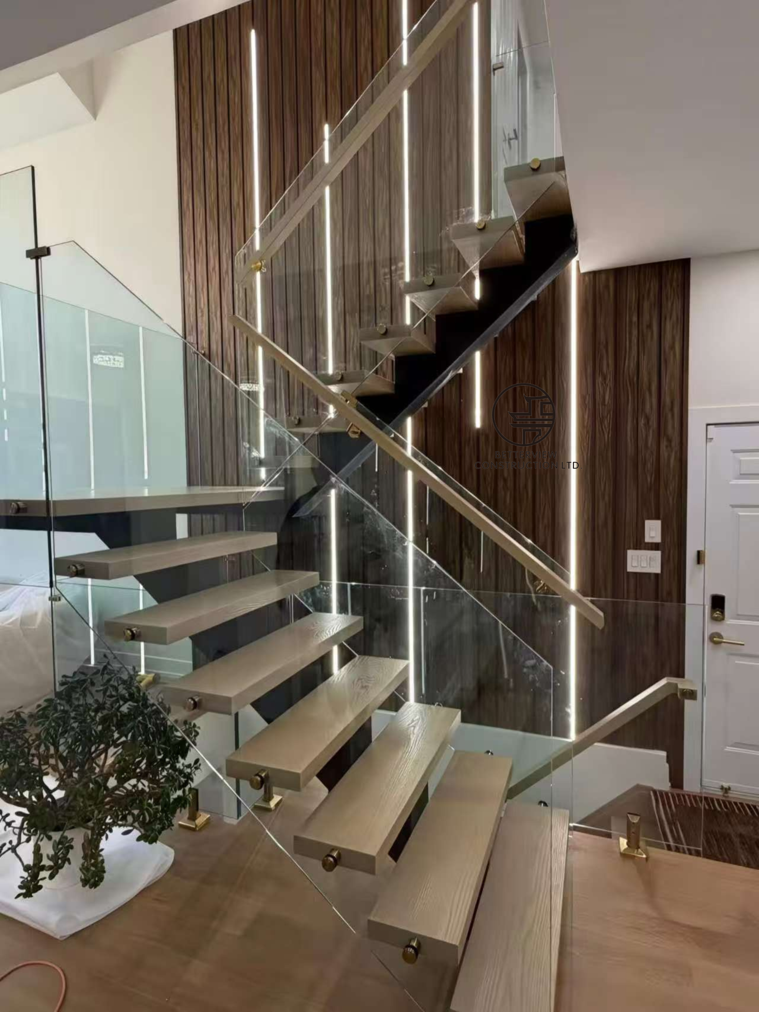 custom floating staircase with glass railing metal stringers and wood slat feature wall in modern Toronto home renovation