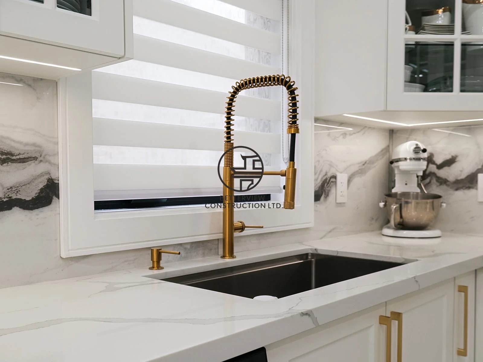 The custom kitchen features white shaker cabinetry, glass display cabinets, quartz countertops, and full-height marble-look backsplash, combining timeless style with everyday functionality.