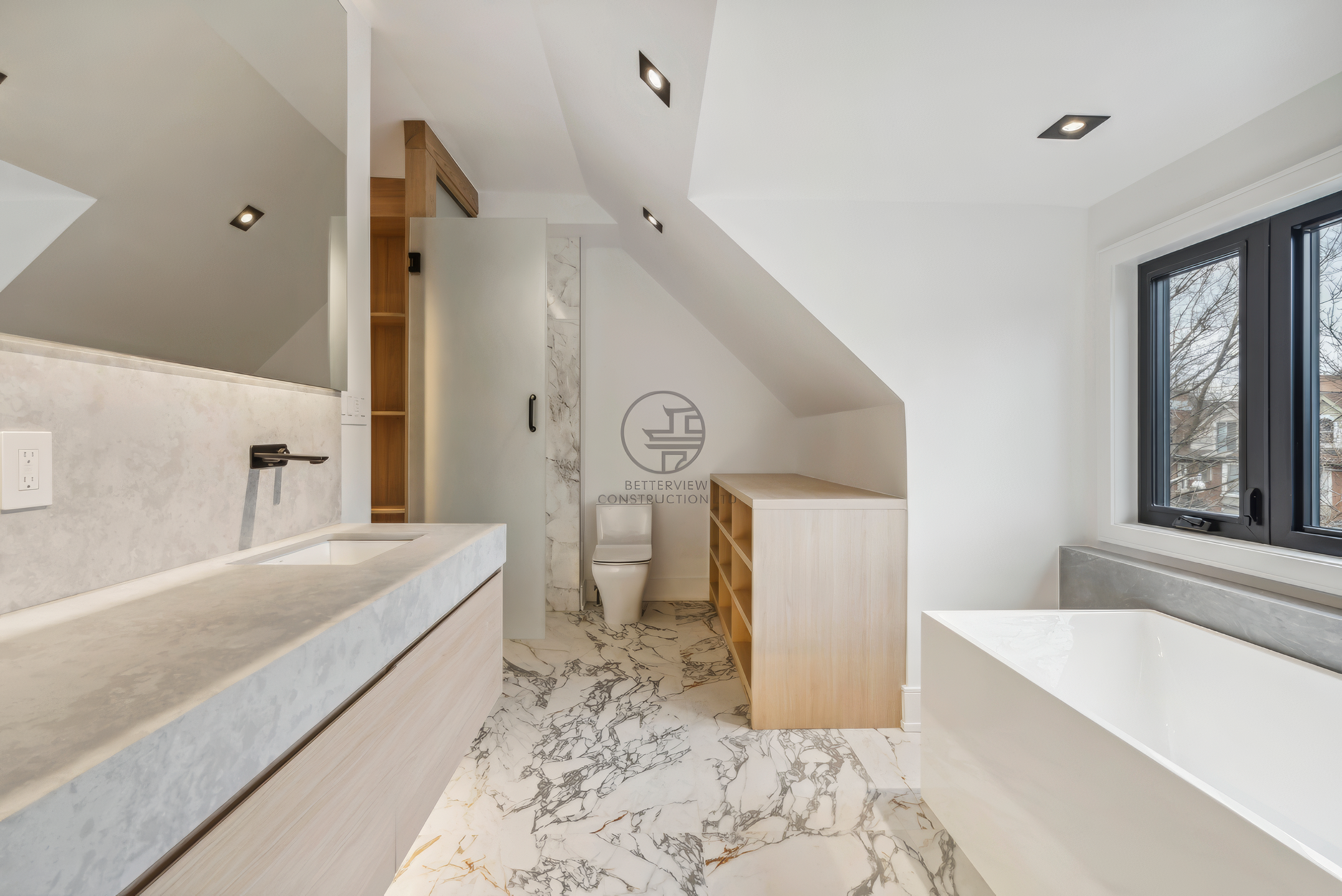 Modern bathroom with freestanding bathtub, double vanity, marble flooring, skylight ceiling, and custom wood cabinetry in a luxury home renovation project