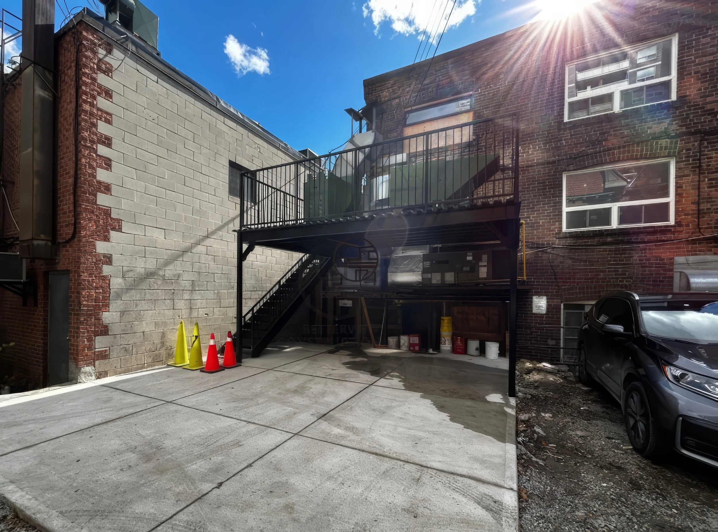 commercial building exterior renovation with metal staircase, balcony deck, and concrete parking area