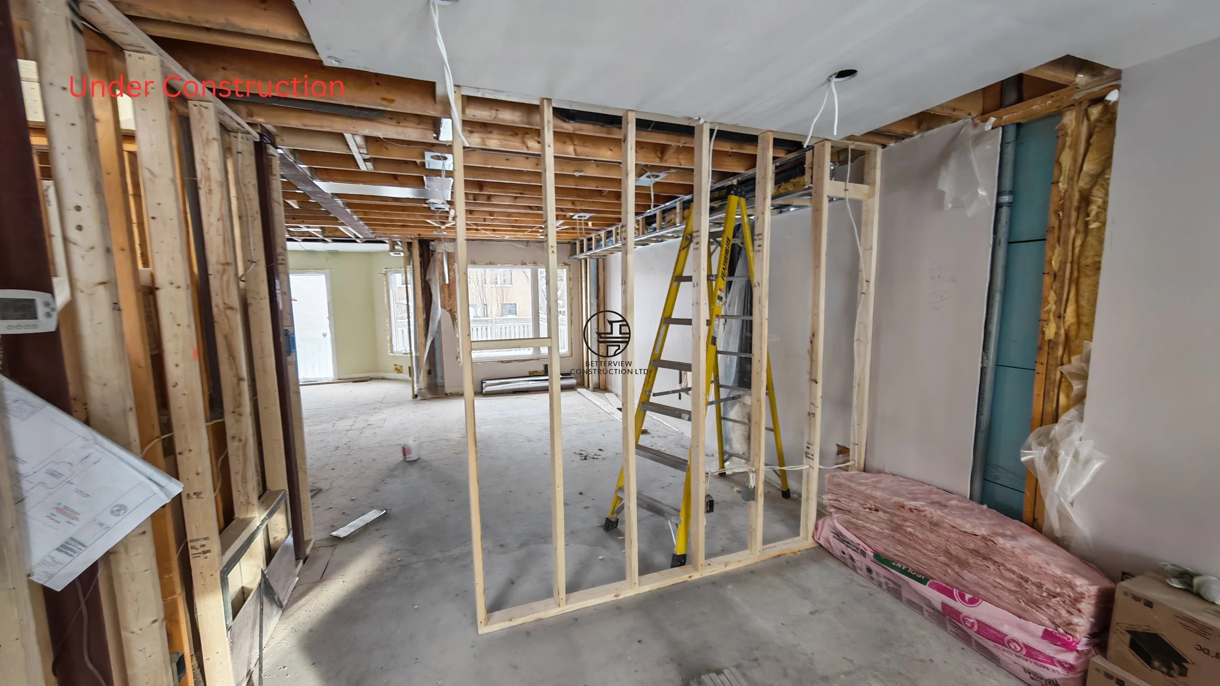 home renovation framing stage with new interior walls exposed studs ceiling joists and construction materials in residential remodeling project