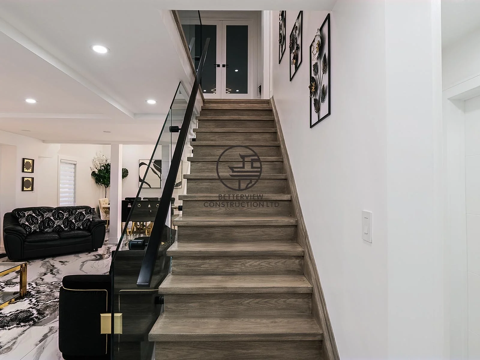 A contemporary staircase with glass railings and wood treads serves as a striking architectural feature, enhancing the home's open layout and modern interior design.
