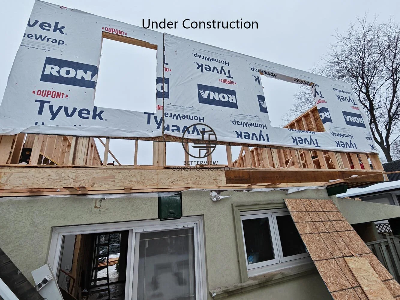 House wrap and exterior sheathing installation during a rear home addition, providing weather protection before exterior finishes.