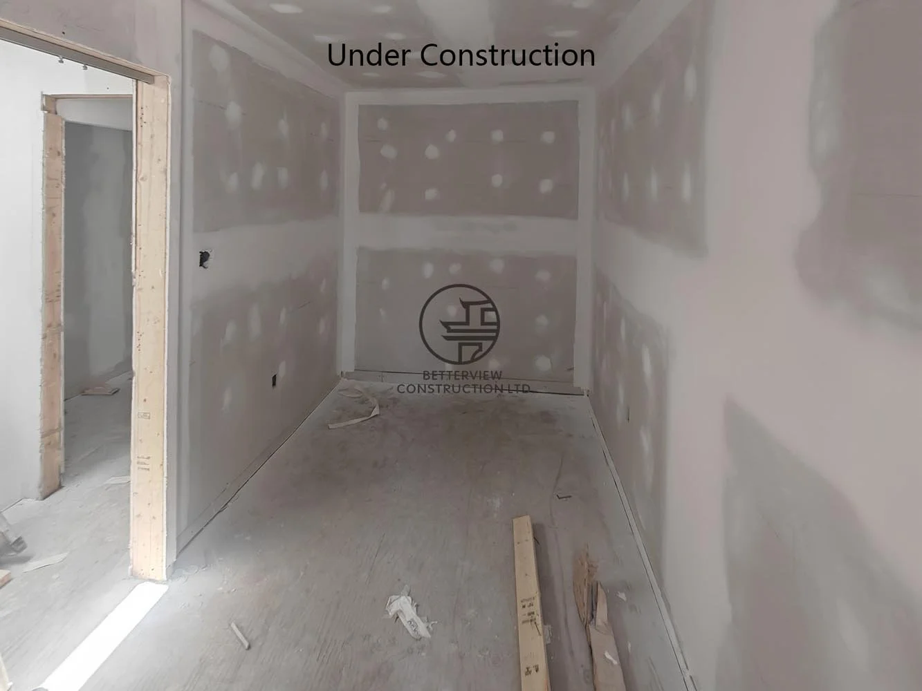 New bedroom during the drywall finishing stage, featuring recessed lighting and preparation for flooring and trim installation.