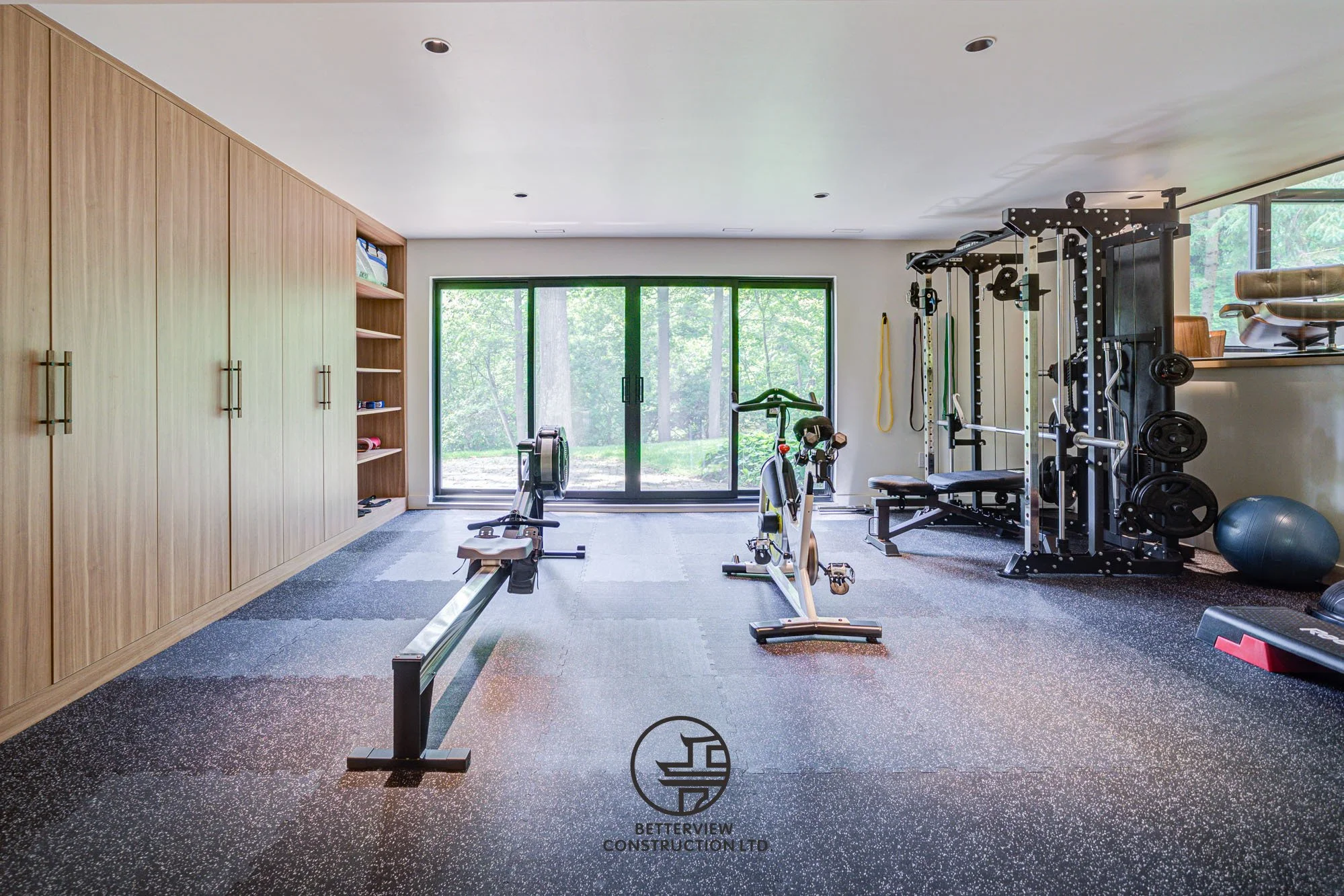 modern basement renovation with home gym equipment and custom wood storage cabinets