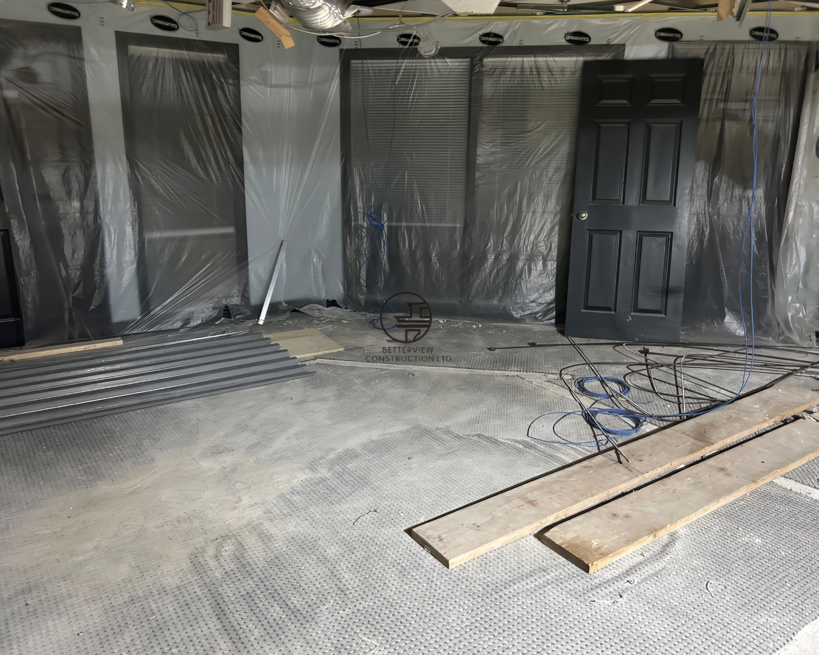 Retail space during renovation preparation with protected walls, exposed flooring, and materials before construction begins