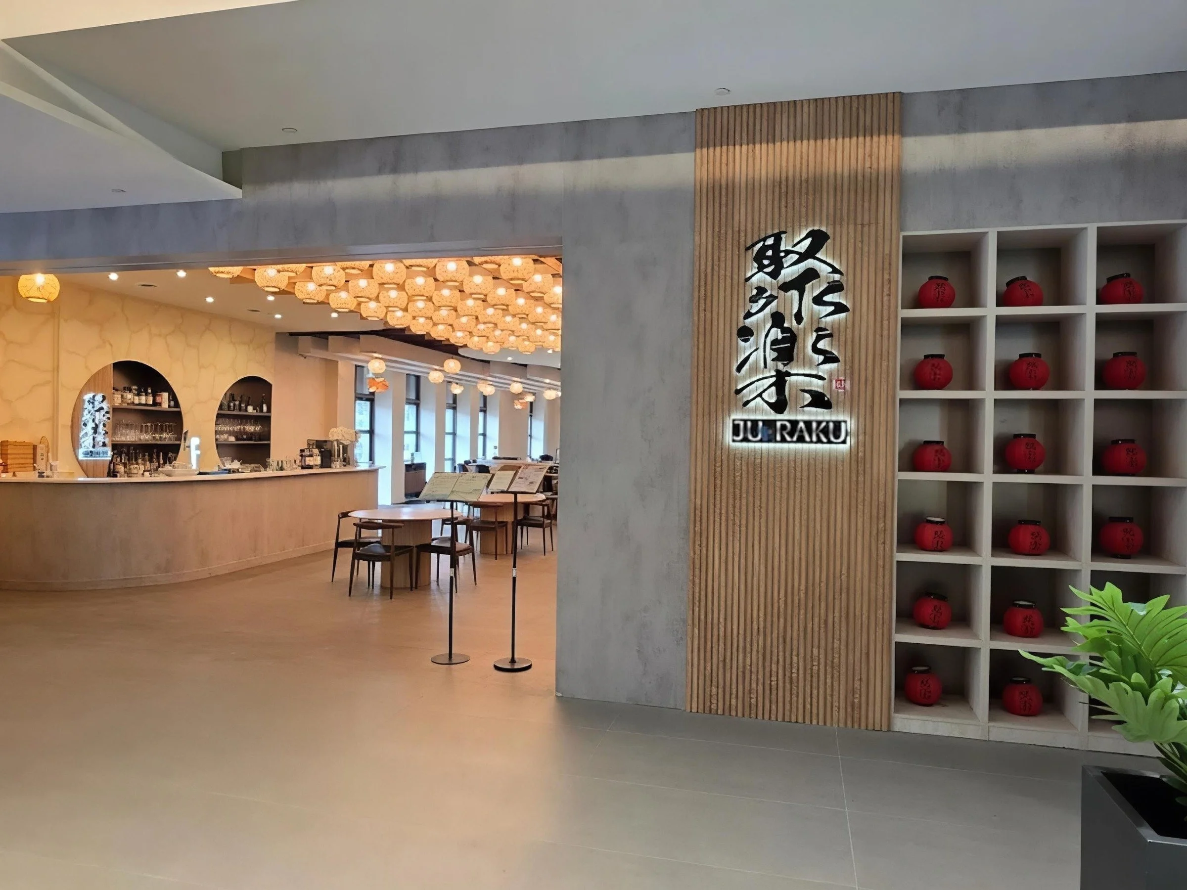 Modern restaurant entrance with custom millwork wall, shelving display, and open dining area design