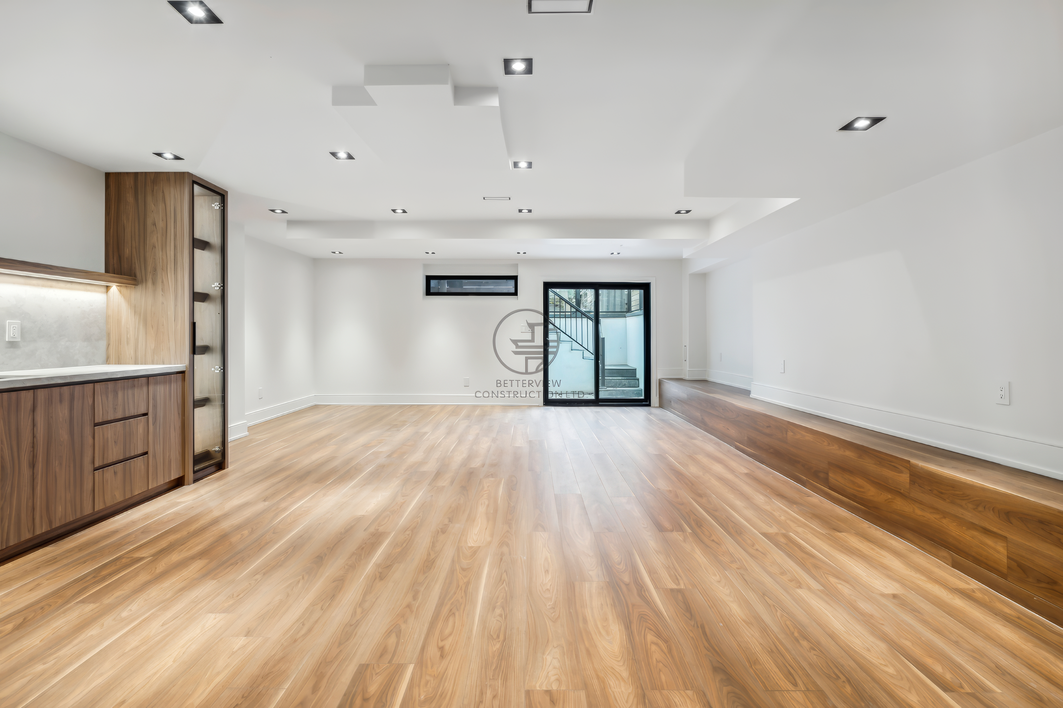 Finished basement with wood flooring, recessed lighting, built-in cabinetry, and open-concept layout in a modern home renovation project