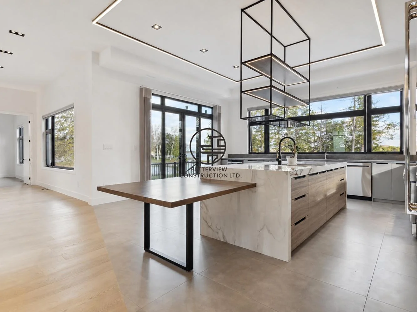 Modern kitchen with island and integrated dining area, large windows, pendant lighting, and open-concept layout with natural light and minimalist design.