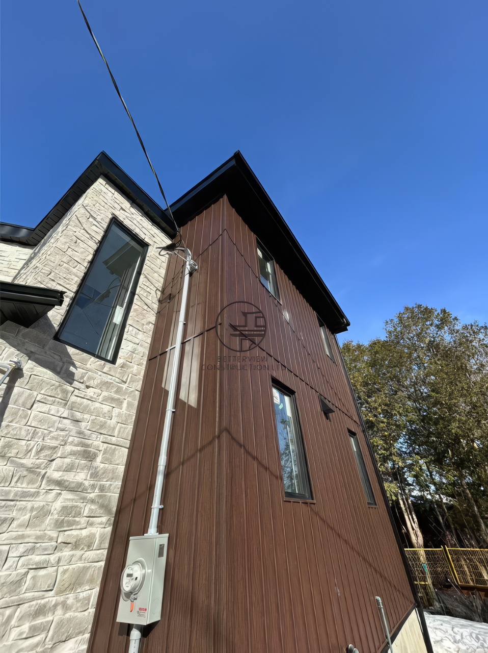 Modern home exterior with wood siding and stone facade, vertical cladding detail on second floor addition