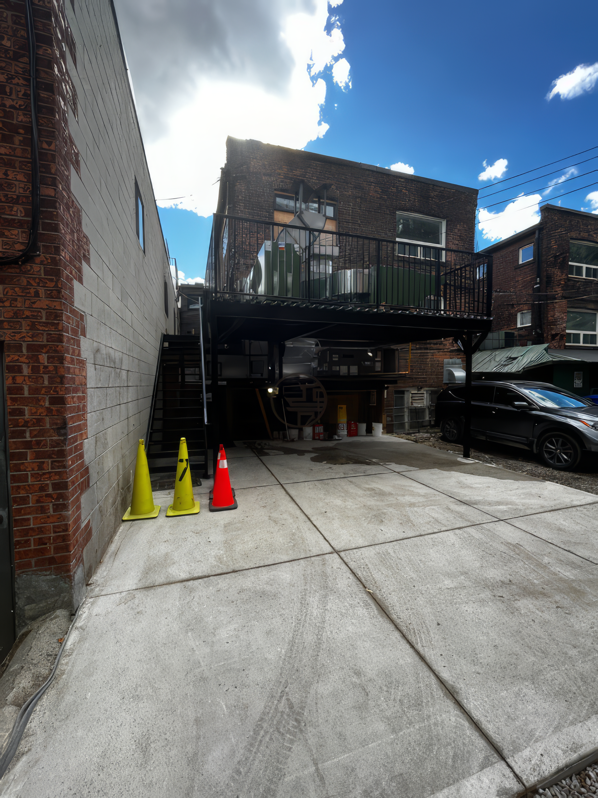 commercial building exterior renovation with elevated metal deck, staircase, and concrete parking area
