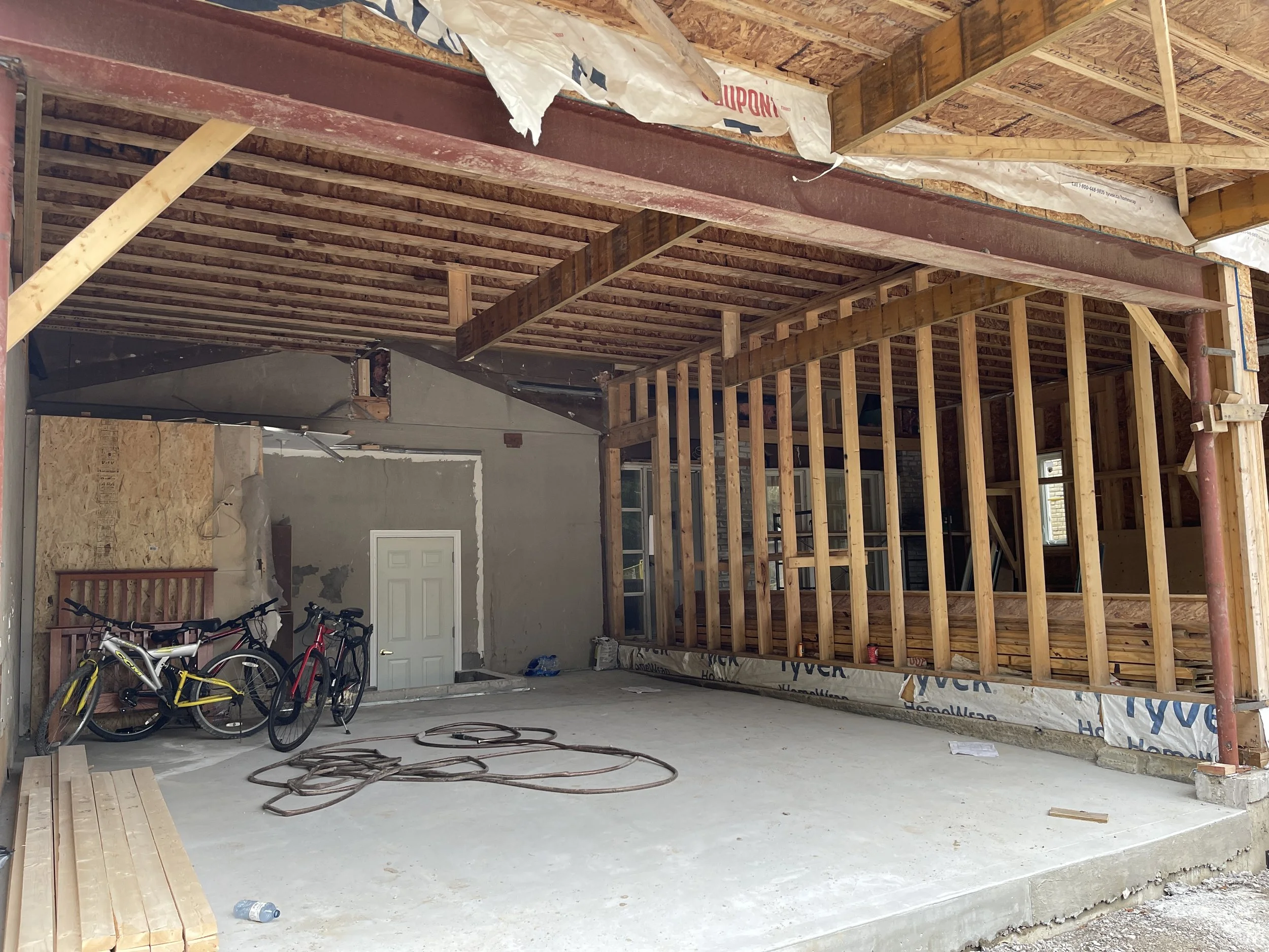 Over-the-garage addition under construction featuring new exterior framing, sheathing, and structural work before exterior finishes.