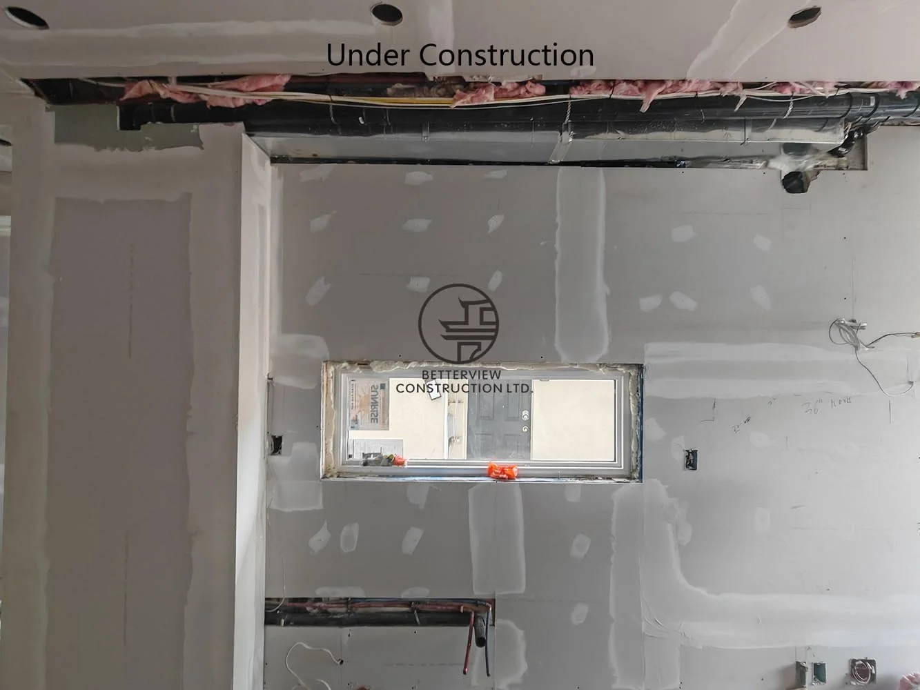Drywall installation around a new window opening, preparing the expanded living space for painting and interior finishing.
