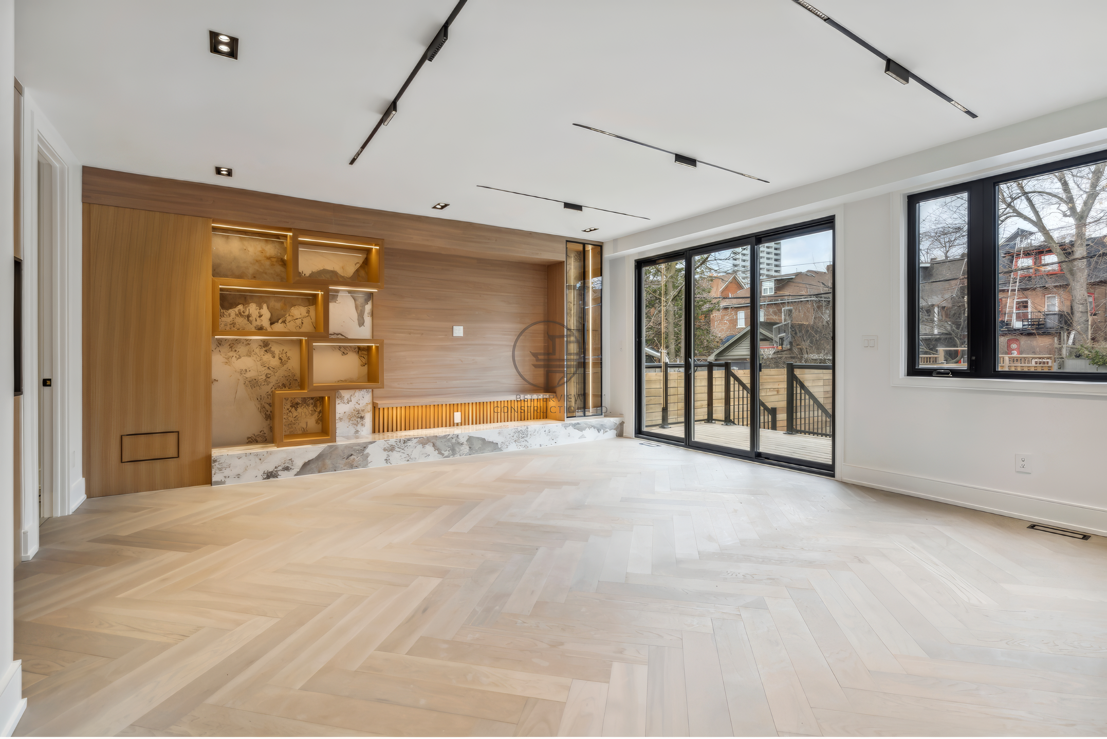 Modern living room with herringbone wood flooring, built-in shelving with accent lighting, large windows, and sliding doors in contemporary home design.