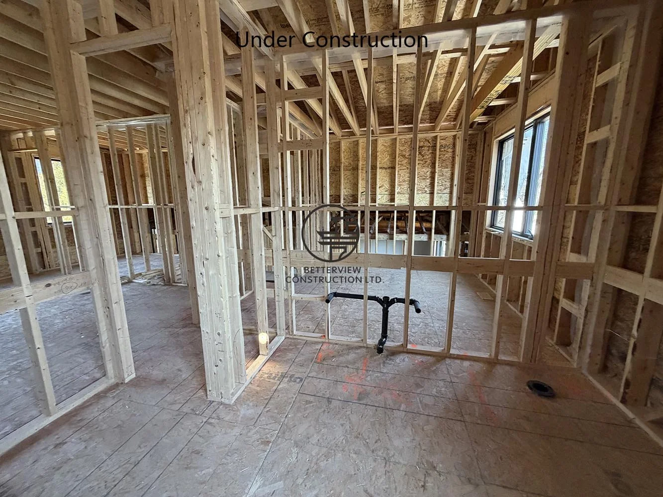Open concept interior framing for a custom home addition, featuring engineered wood framing and structural beam installation.