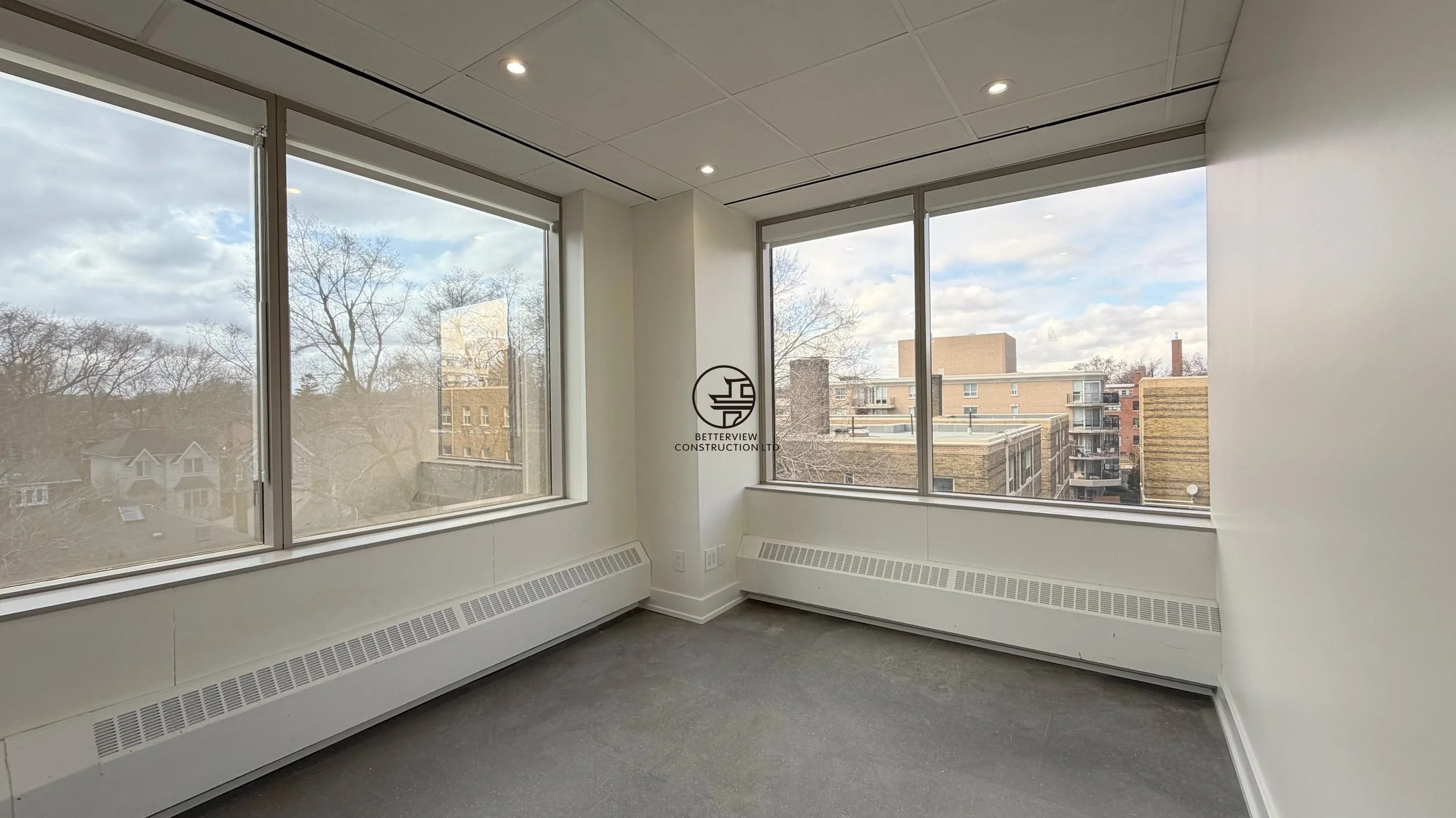 Corner office with large windows, panoramic city view, and natural light in modern commercial renovation