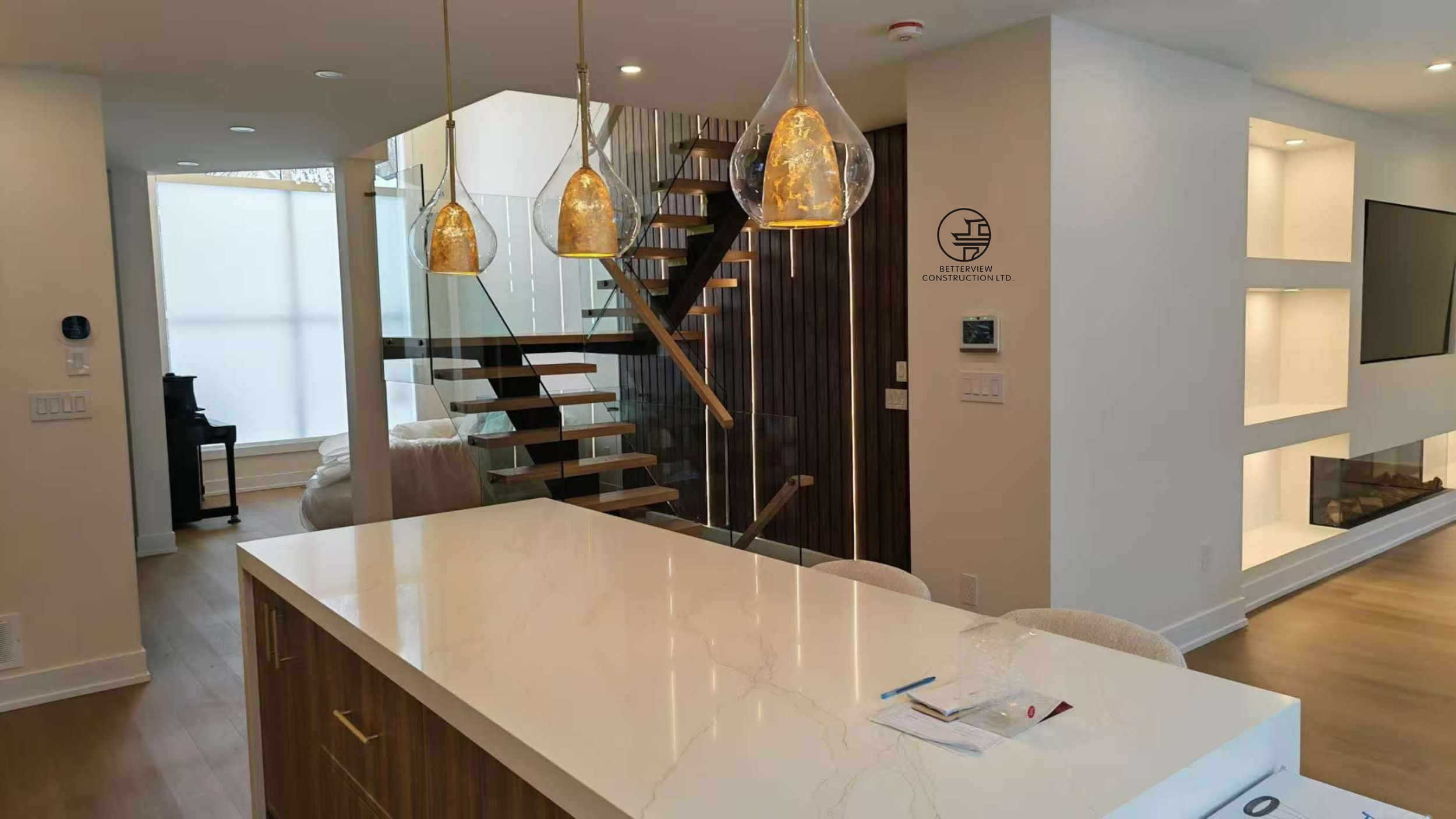 modern kitchen island with pendant lighting open concept layout and floating staircase with wood accent wall in Toronto home renovation