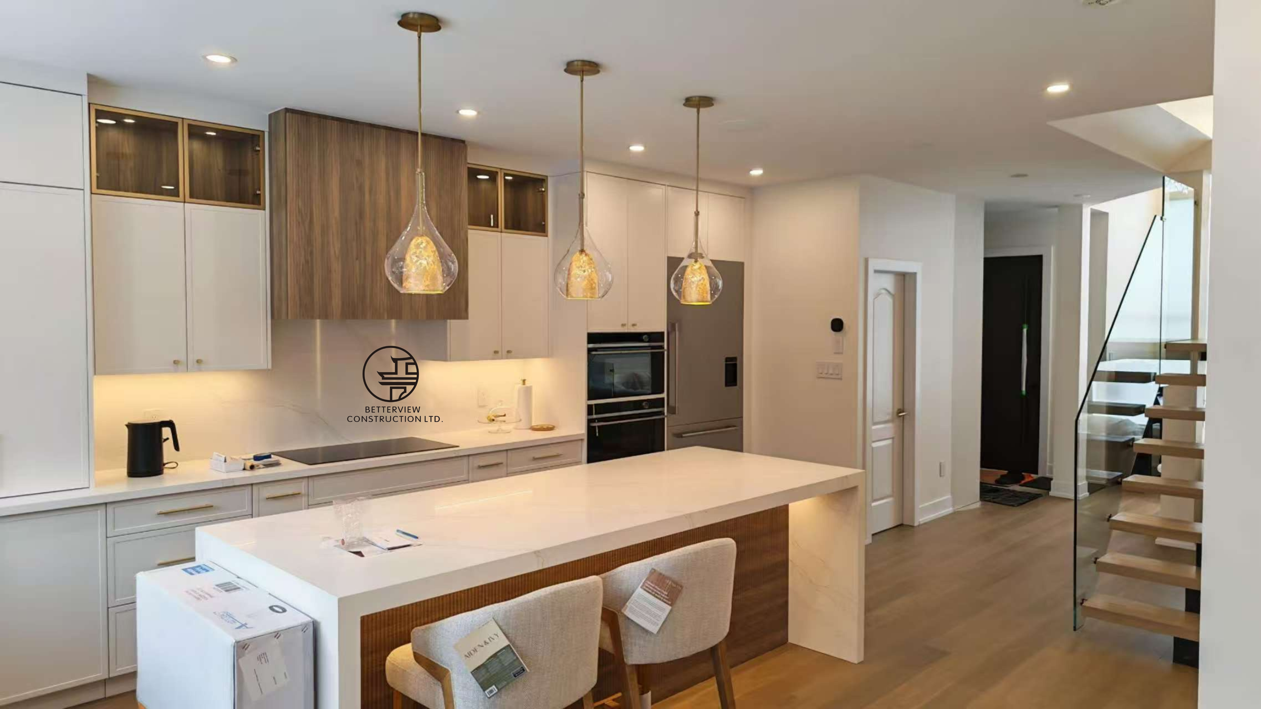 modern kitchen with large island pendant lighting custom cabinetry and open staircase in Toronto home renovation