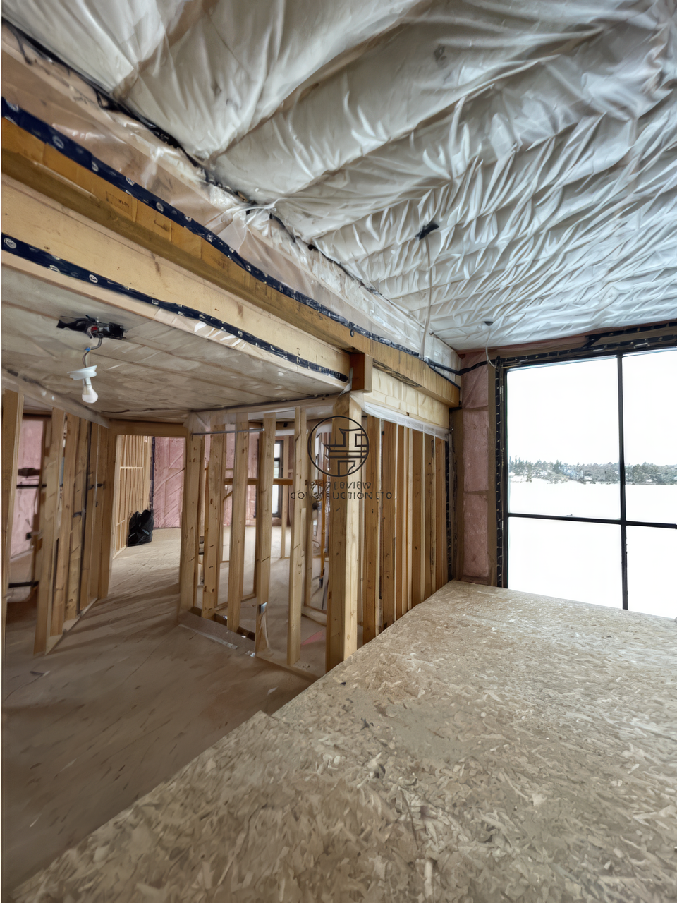 Interior framing and spray foam insulation during home renovation with open floor layout and large window