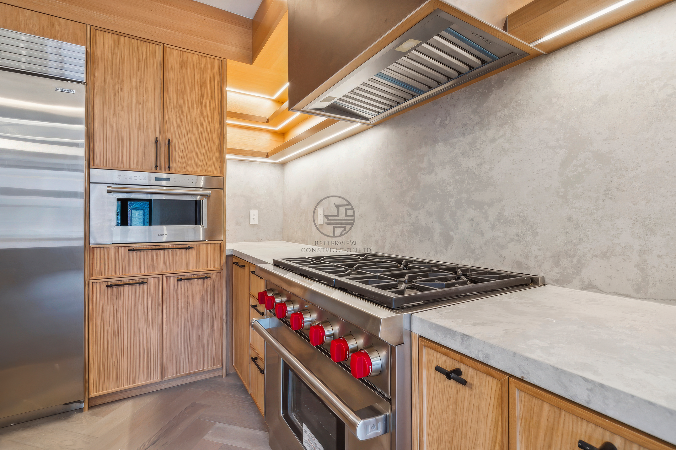 Modern kitchen with gas range, custom wood cabinets, quartz countertops, stainless steel appliances, and built-in range hood in a luxury home renovation project