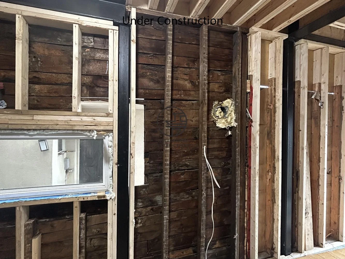 Interior framing exposing the original structure before integrating the new rear addition and completing the open concept layout reconfiguration.