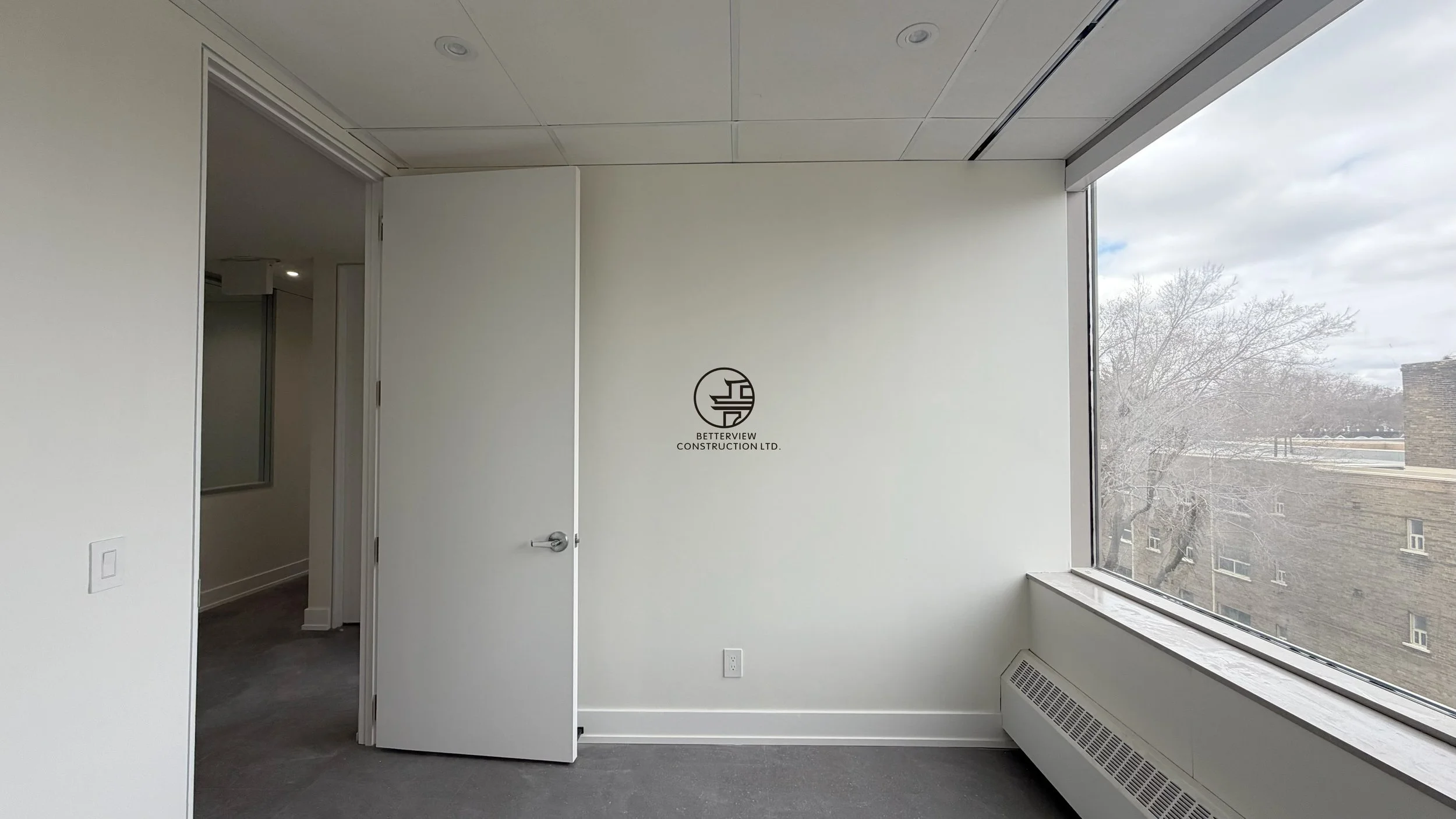 Modern office room with large window, open door, and clean interior design in commercial renovation