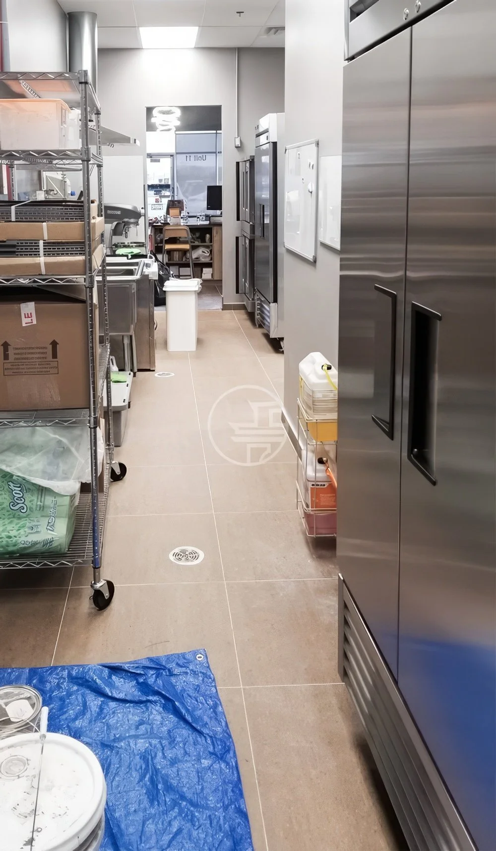 Commercial kitchen renovation in Toronto featuring stainless steel equipment, storage racks, and back-of-house cafe workspace design