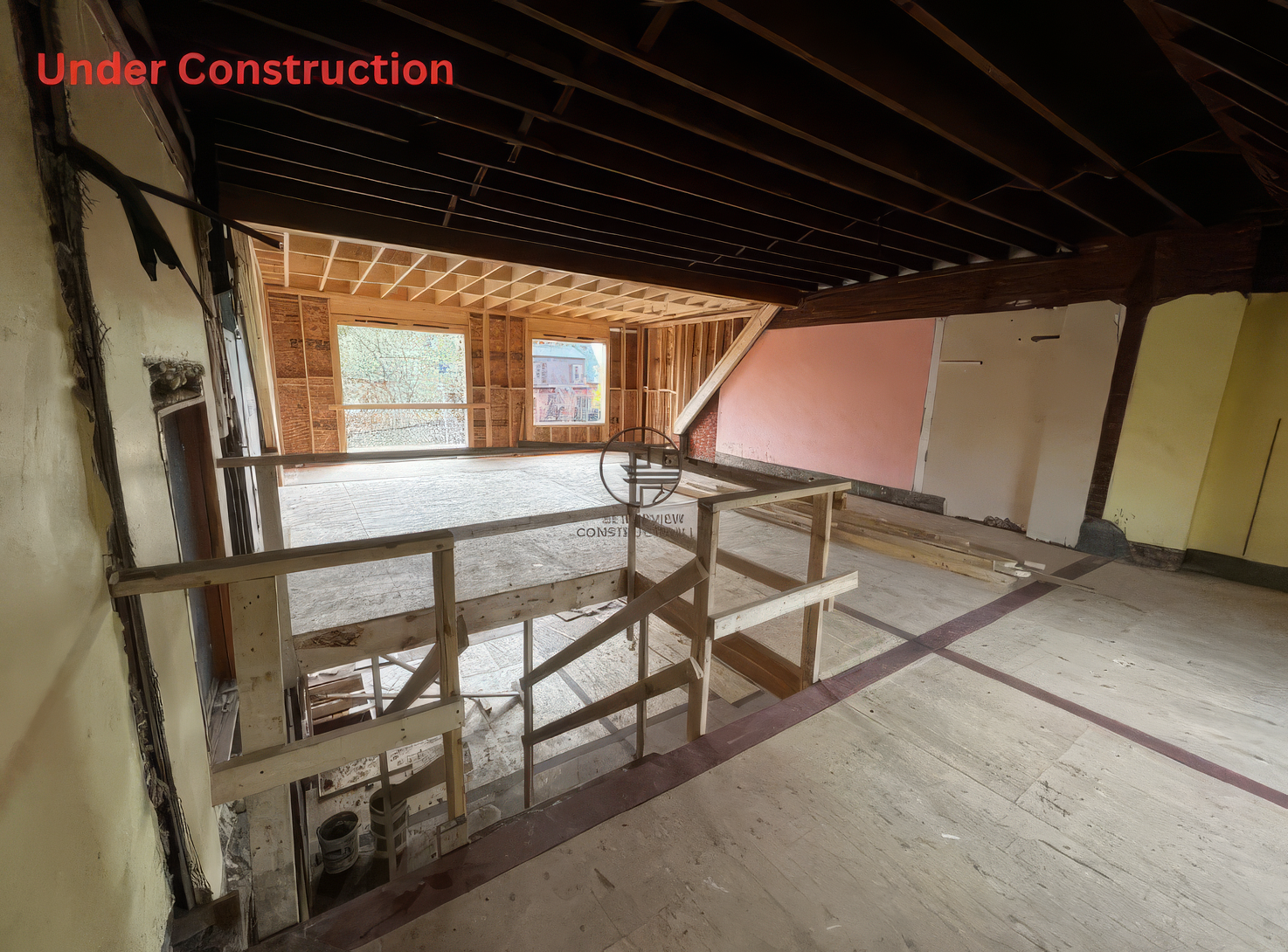 Under construction open-concept interior with exposed ceiling beams, new framing, staircase railing, and subfloor during residential home renovation project