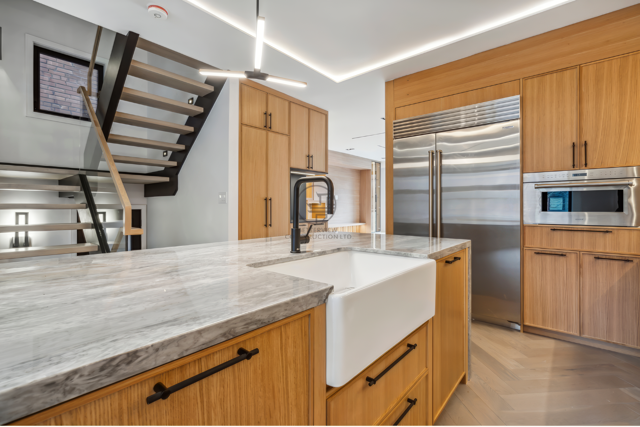 Modern kitchen with large island, farmhouse sink, custom wood cabinetry, stainless steel appliances, and open-concept layout in a luxury home renovation project