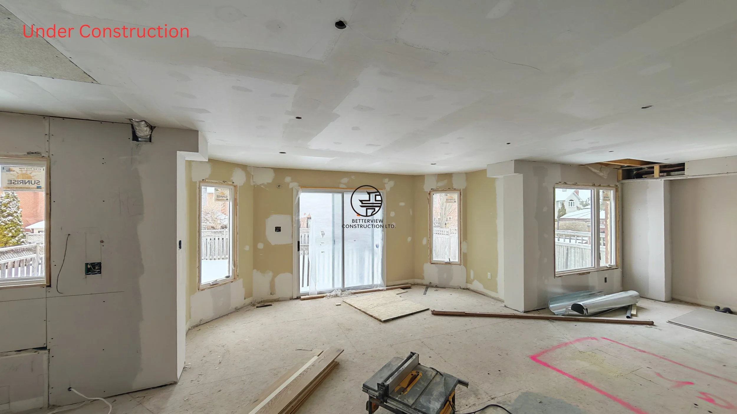home renovation in progress with drywall installation open concept layout large windows and construction tools in unfinished residential interior
