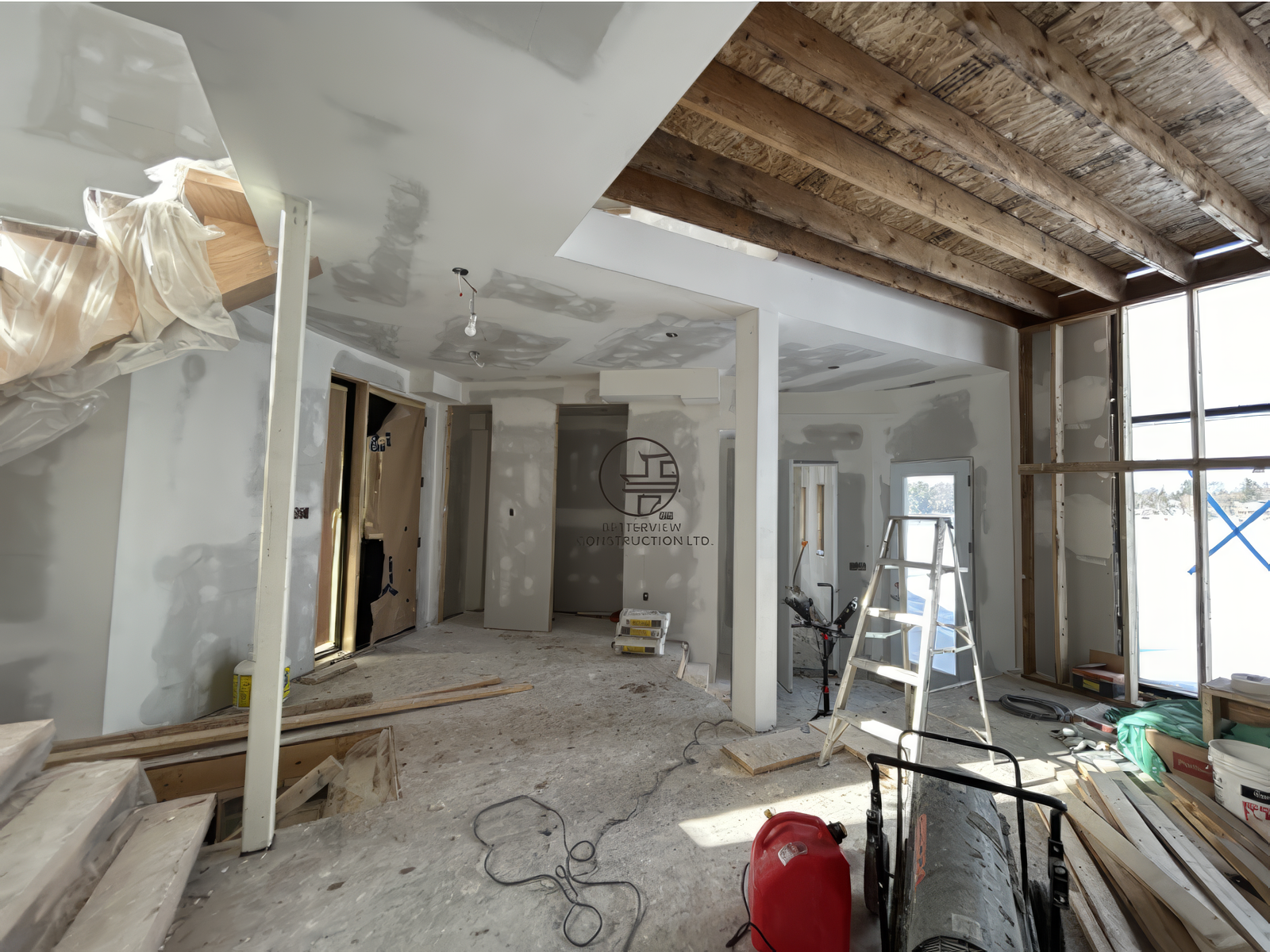 Open concept home renovation with drywall installation, exposed ceiling beams and structural upgrades in residential construction project