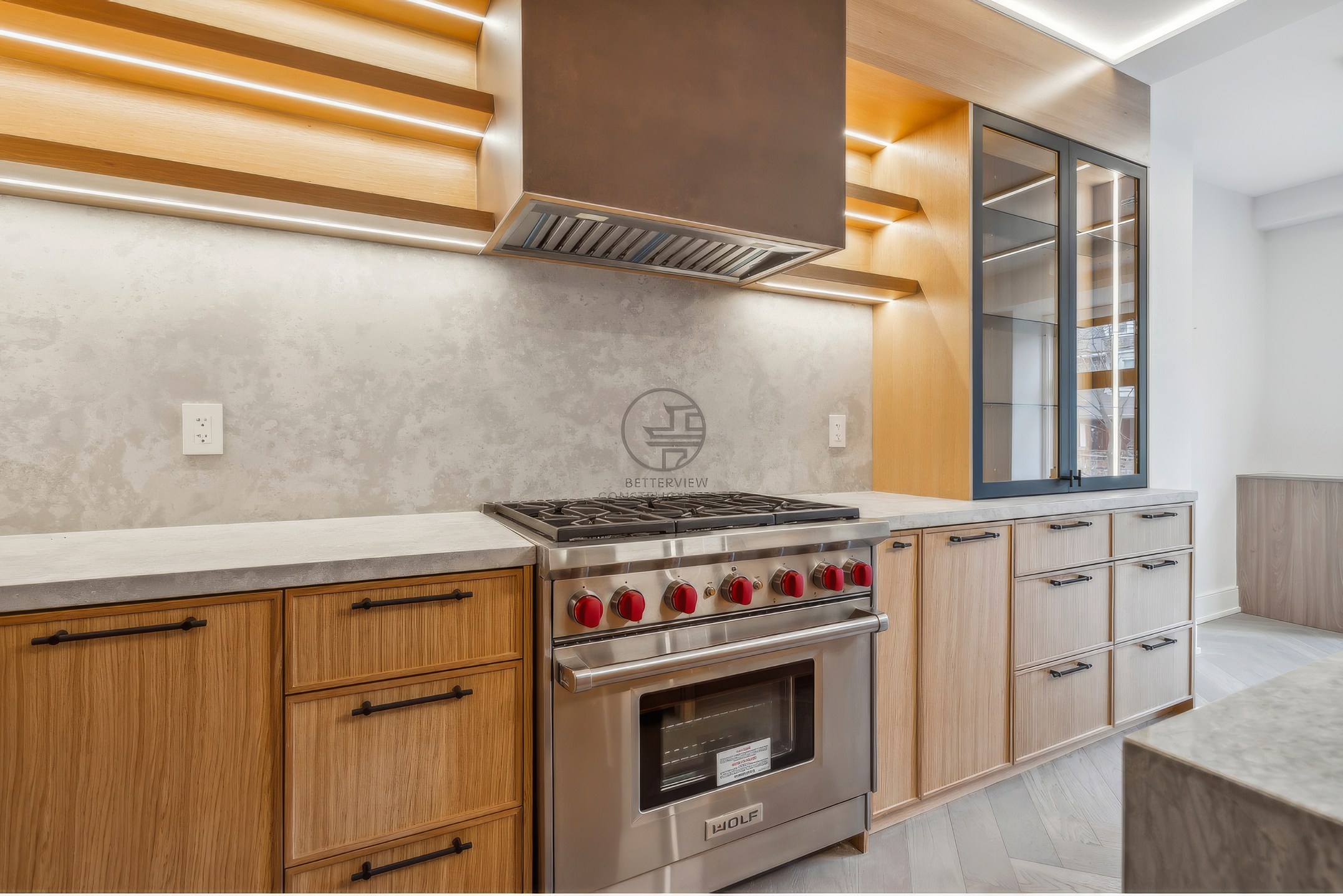 Modern kitchen with gas range, custom wood cabinetry, quartz countertops, glass display cabinet, and built-in range hood in a luxury home renovation project