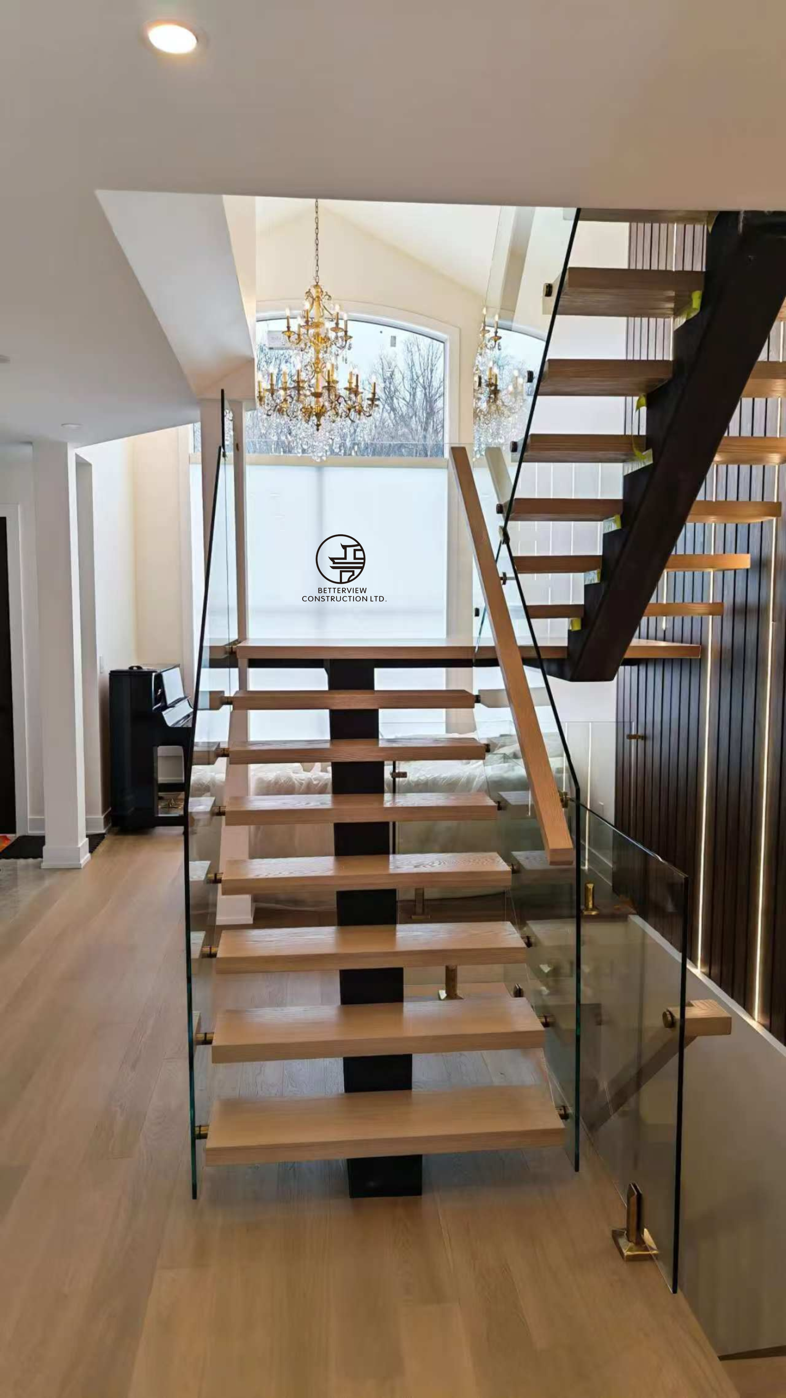 modern floating staircase with glass railing wood treads chandelier feature and open concept interior in luxury Toronto home renovation