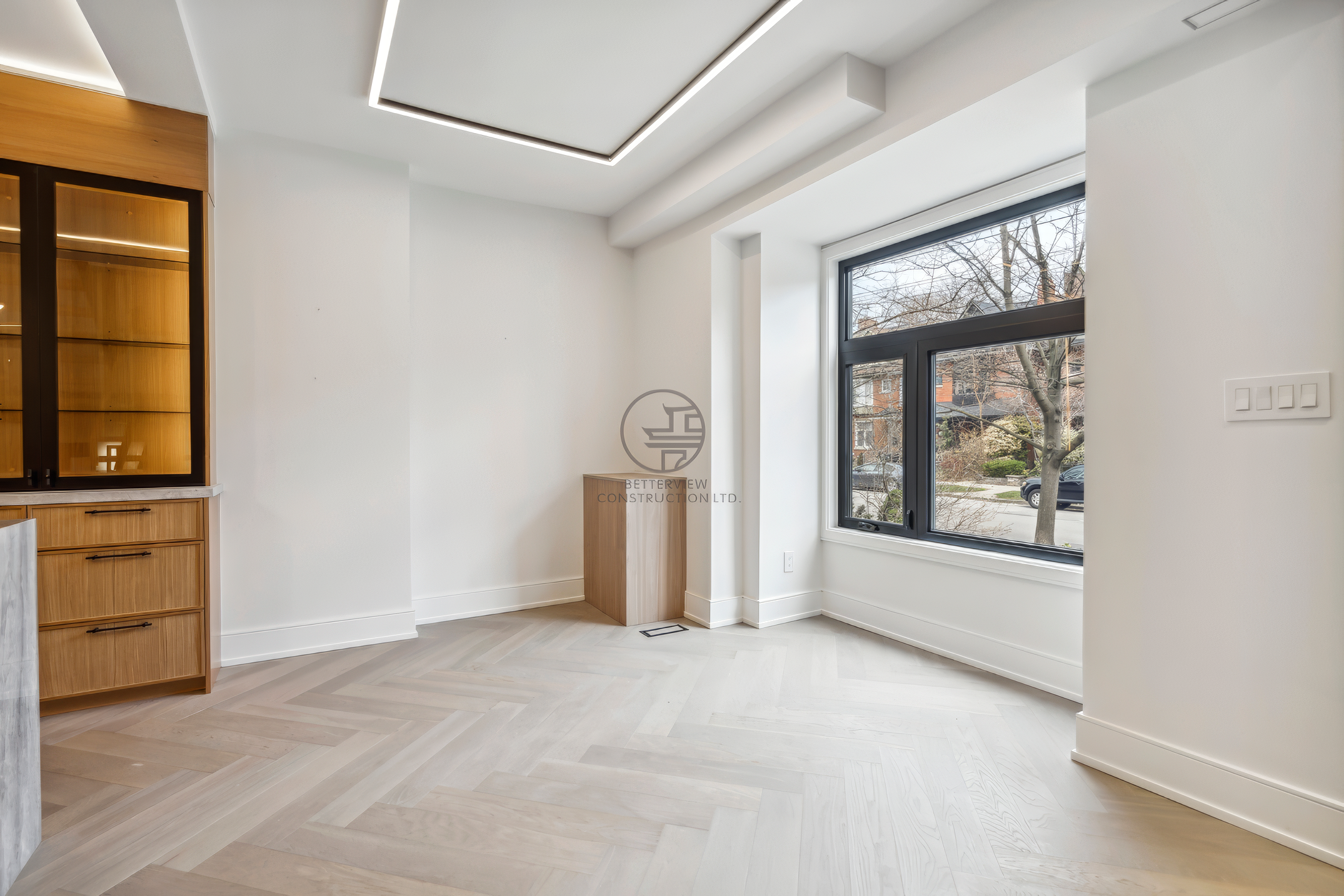 Modern bedroom with herringbone wood flooring, large window, recessed LED ceiling lighting, and built-in cabinetry with minimalist design.