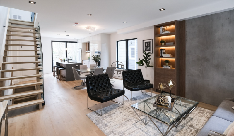 Open-concept living room renovation featuring modern staircase design, custom built-in shelving with accent lighting, and contemporary interior finishes in a GTA home