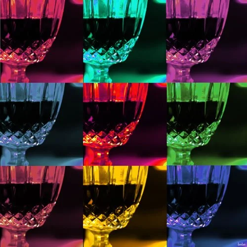 Nine colorful glasses of wine arranged in a 3x3 grid, each with different colored lighting.