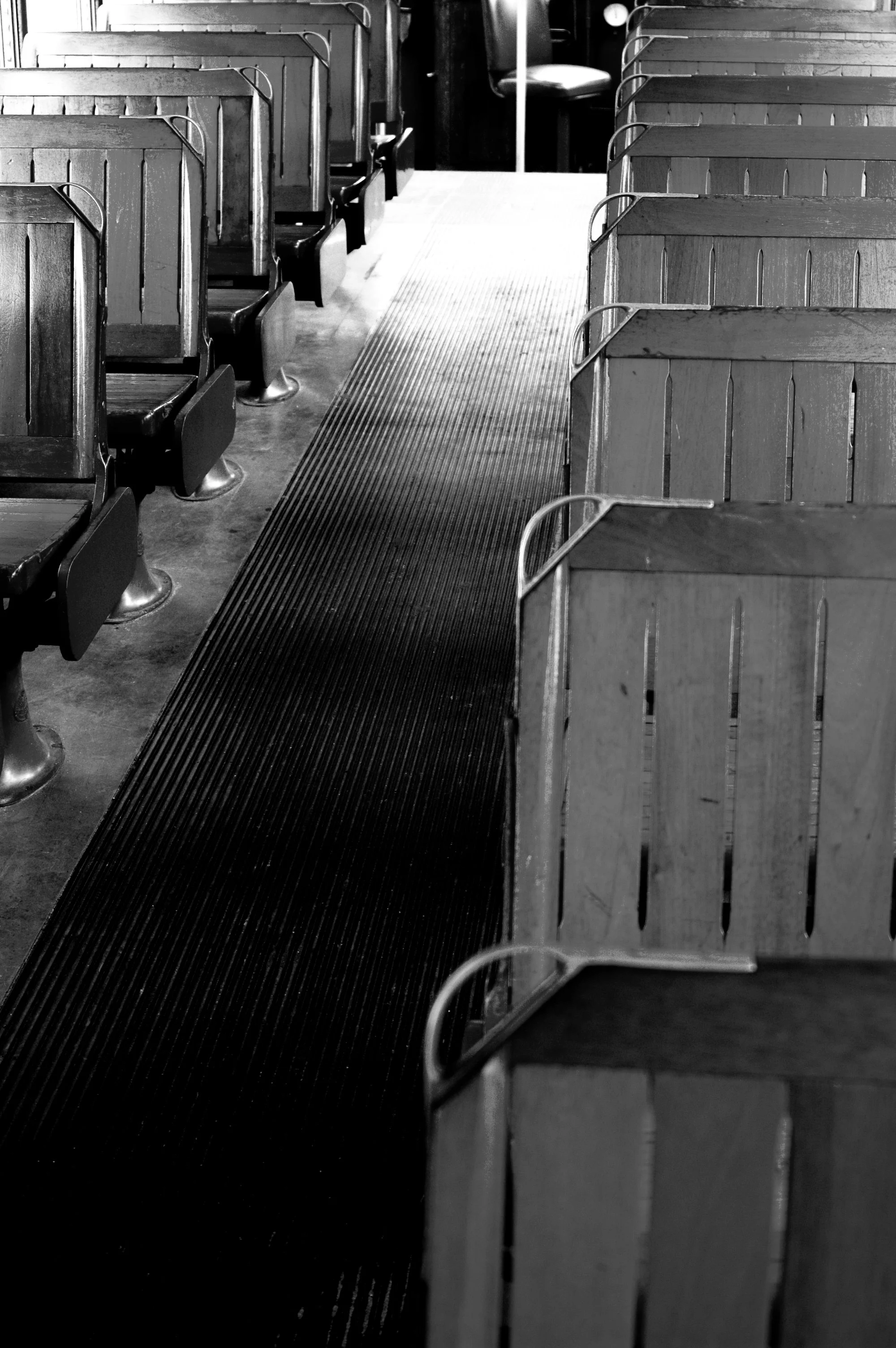 Empty dining booth with wooden partitions and metal chairs in a restaurant or cafe, seen from an aisle with ribbed flooring.